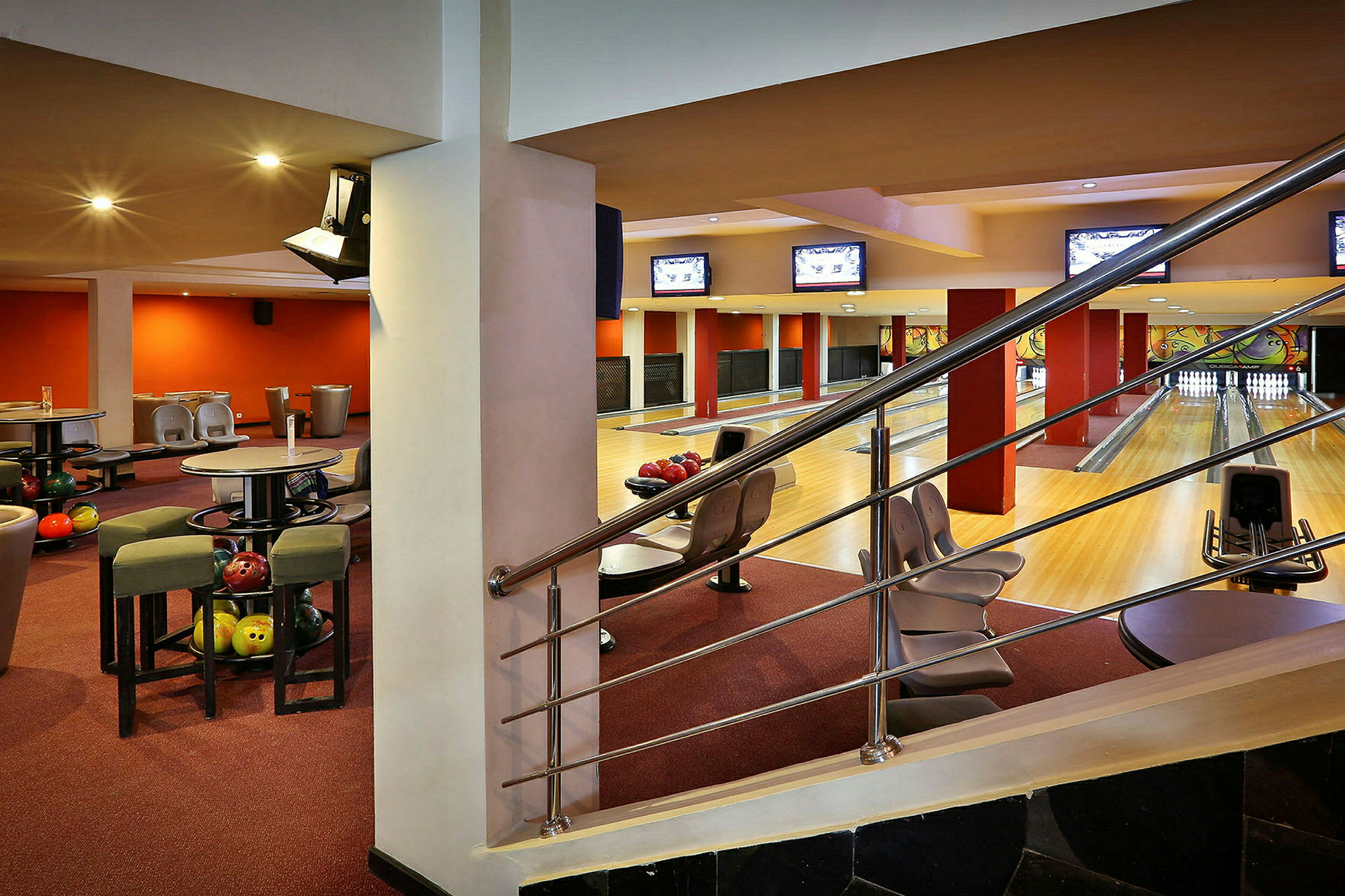 Ett inomhus bowlinghall med banor, sittplatser och bowlingklot. Rummet är inrett i varma färger. (AI-genererad text)