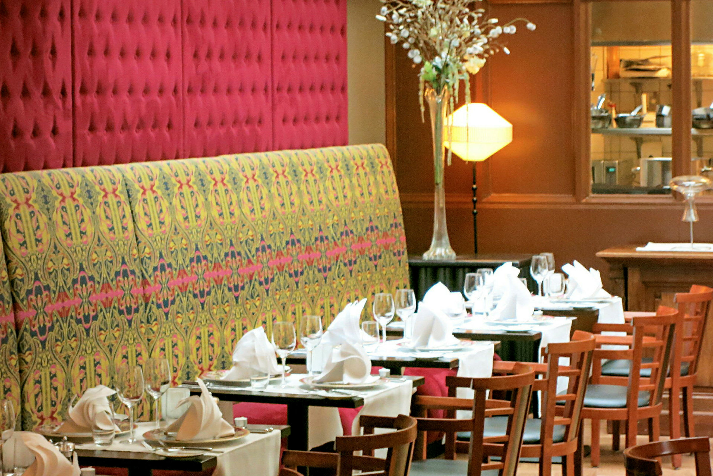 En restaurang interiör med dukade bord med vita dukar, glas, tallrikar och vikta servetter. (AI-genererad text)