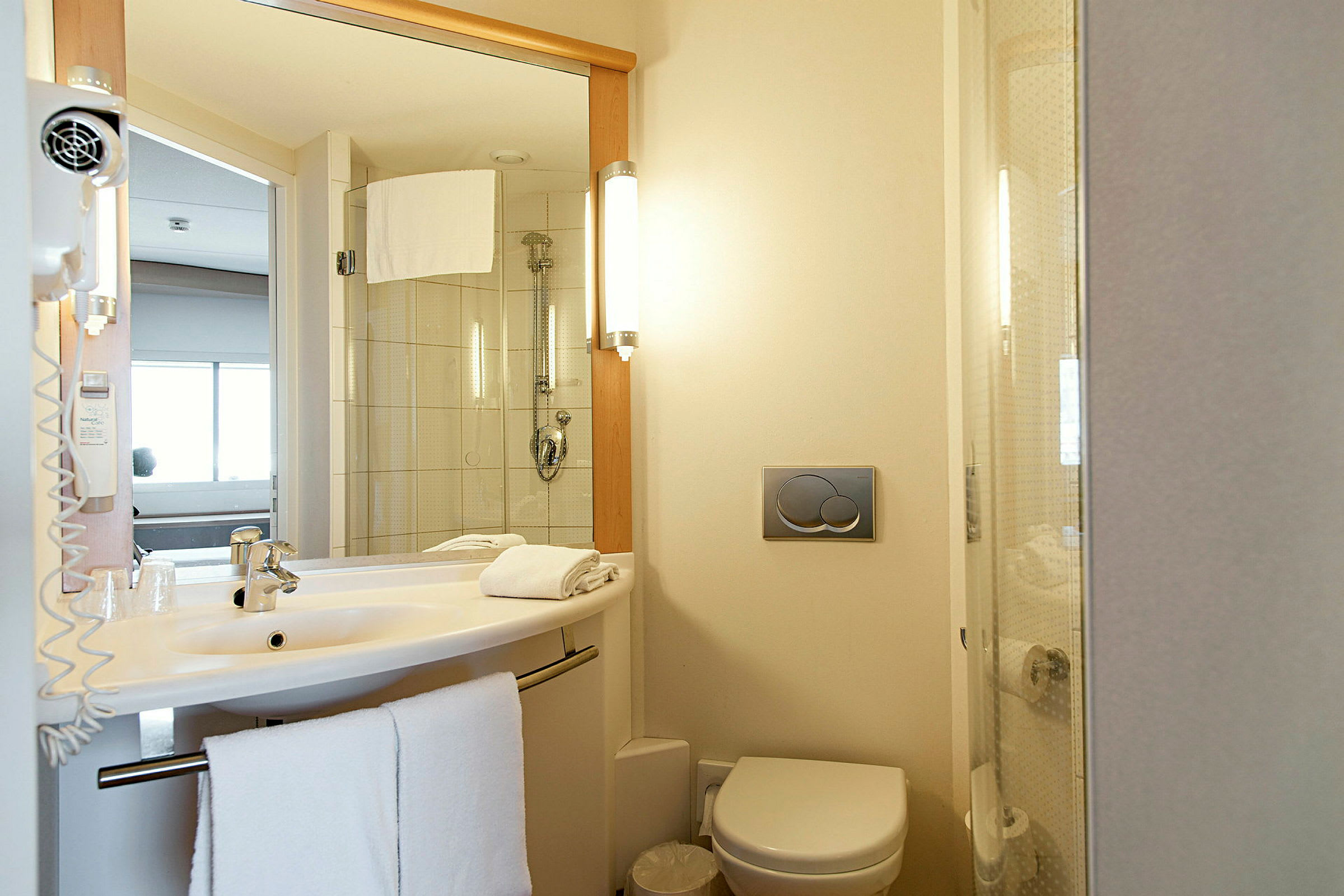 Ett hotellbadrum med handfat, toalett och dusch. (AI-genererad text)