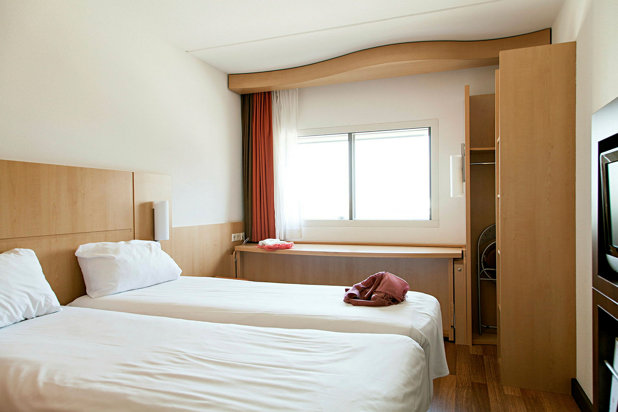 Ett hotellrum med två enkelsängar och ett fönster med ljusinsläpp. (AI-genererad text)