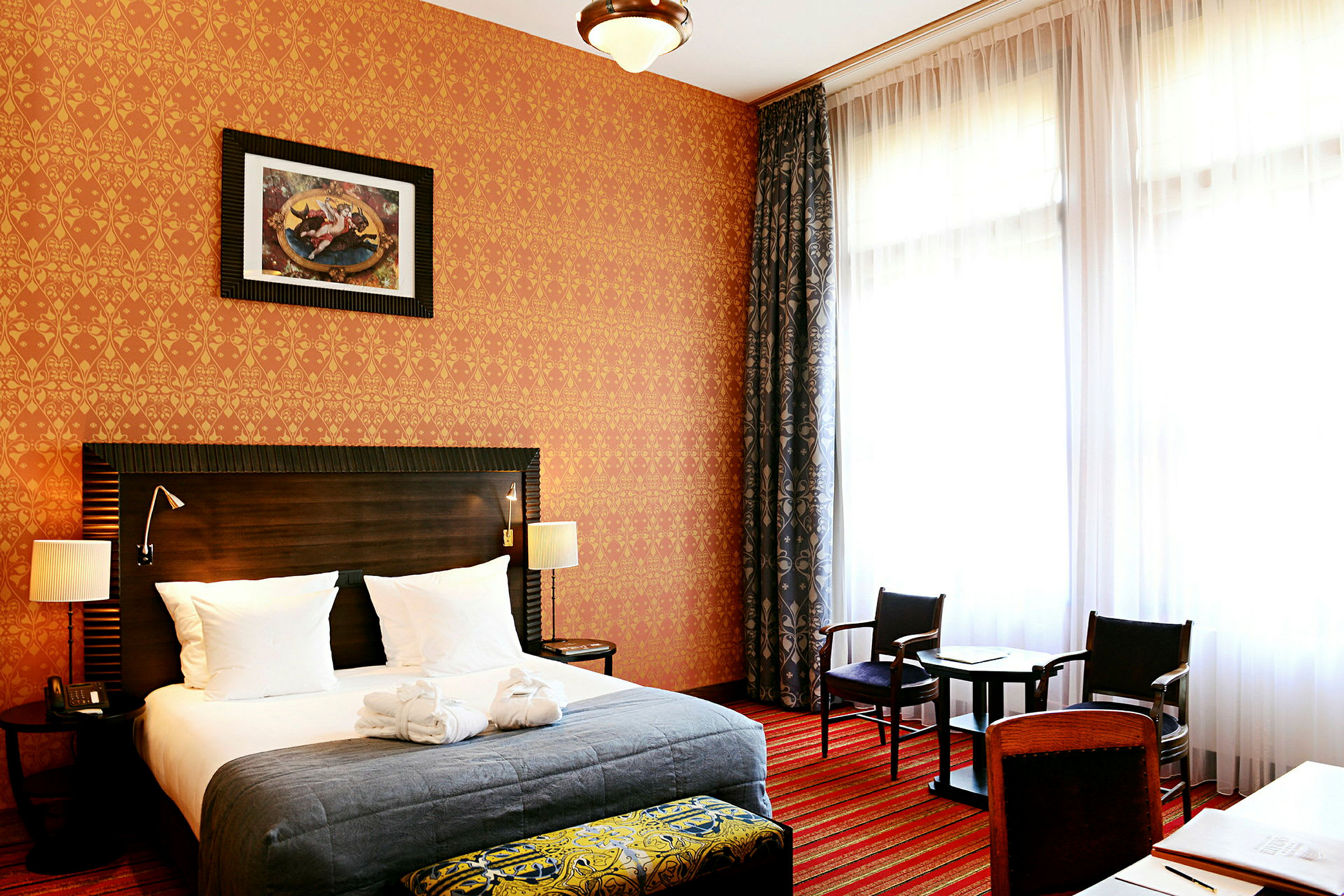 Ett hotellrum med en stor säng, sittmöbler och ett fönster med gardiner. (AI-genererad text)