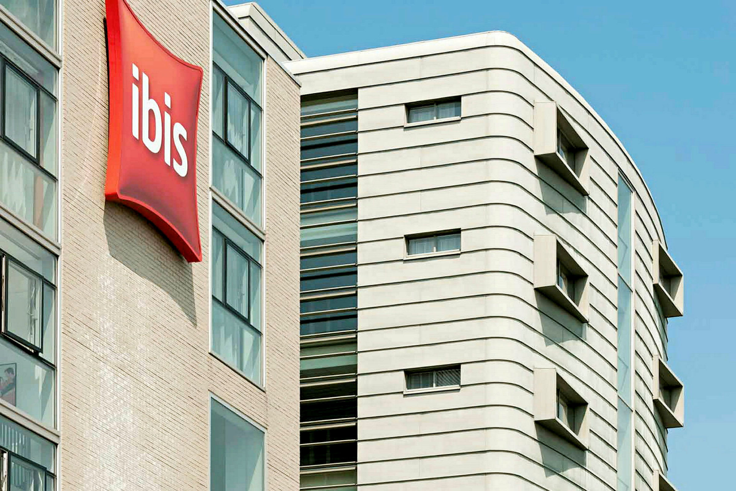 Flera våningar av en modern byggnad med ett tydligt rött ibisskylt. (AI-genererad text)