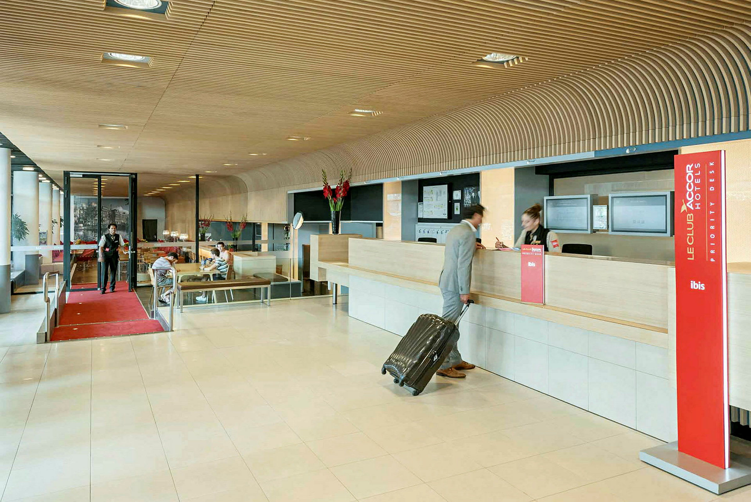 Hotellobby med reception, en person med resväska checkar in. (AI-genererad text)