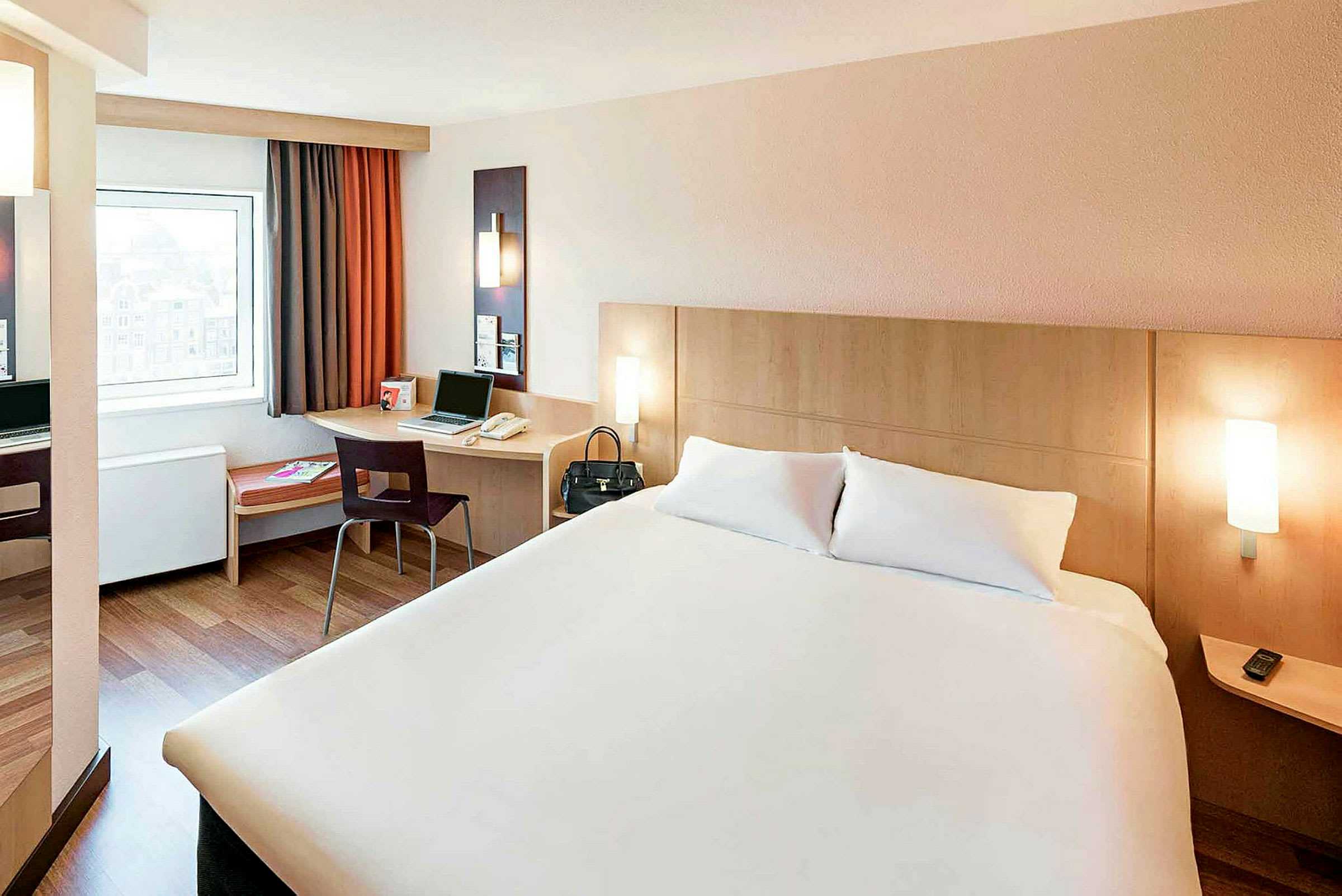 Hotellrum med en dubbelsäng, ett skrivbord med en stol och ett fönster. (AI-genererad text)