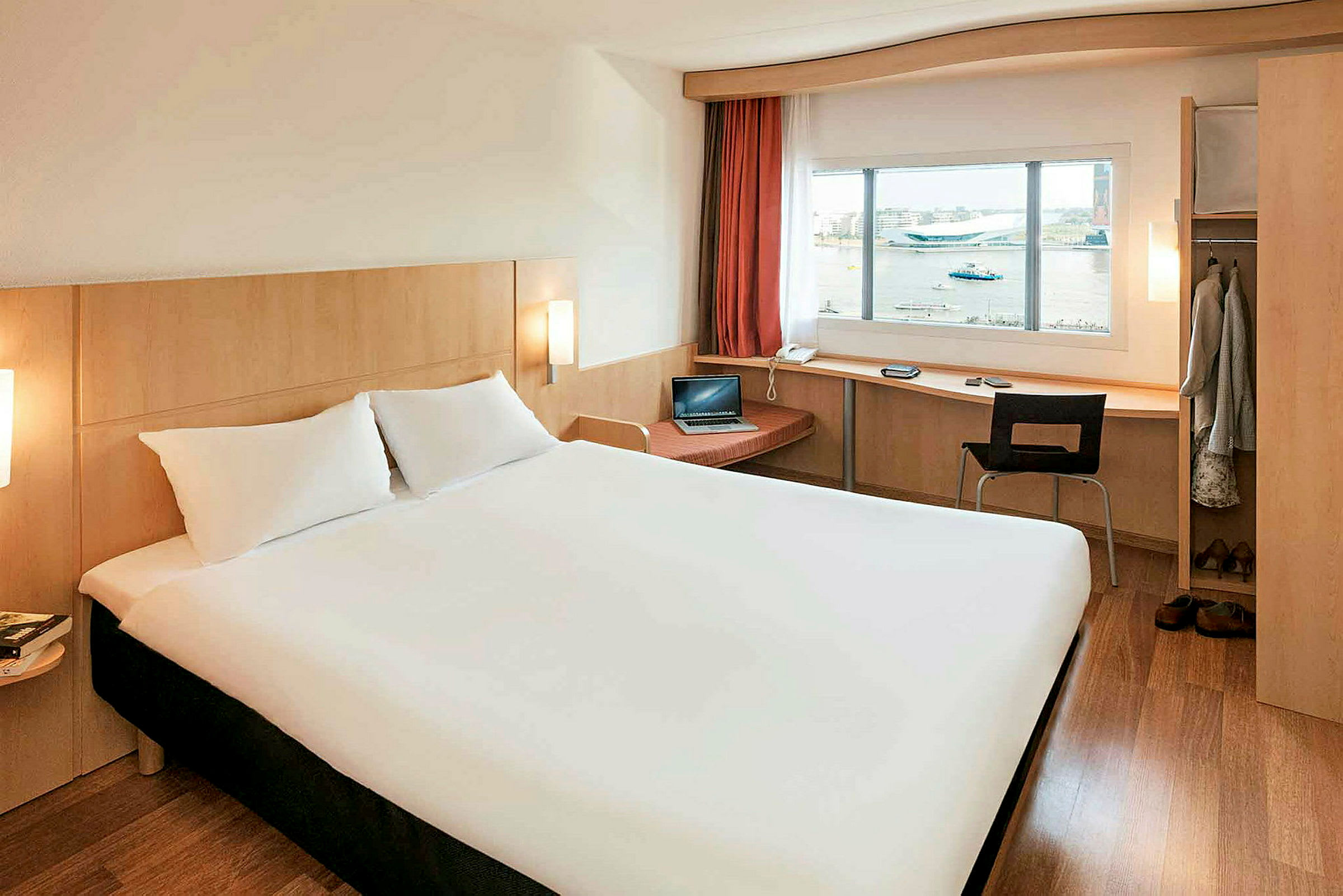 Ett hotellrum med en stor säng, skrivbord vid fönstret och garderob. (AI-genererad text)