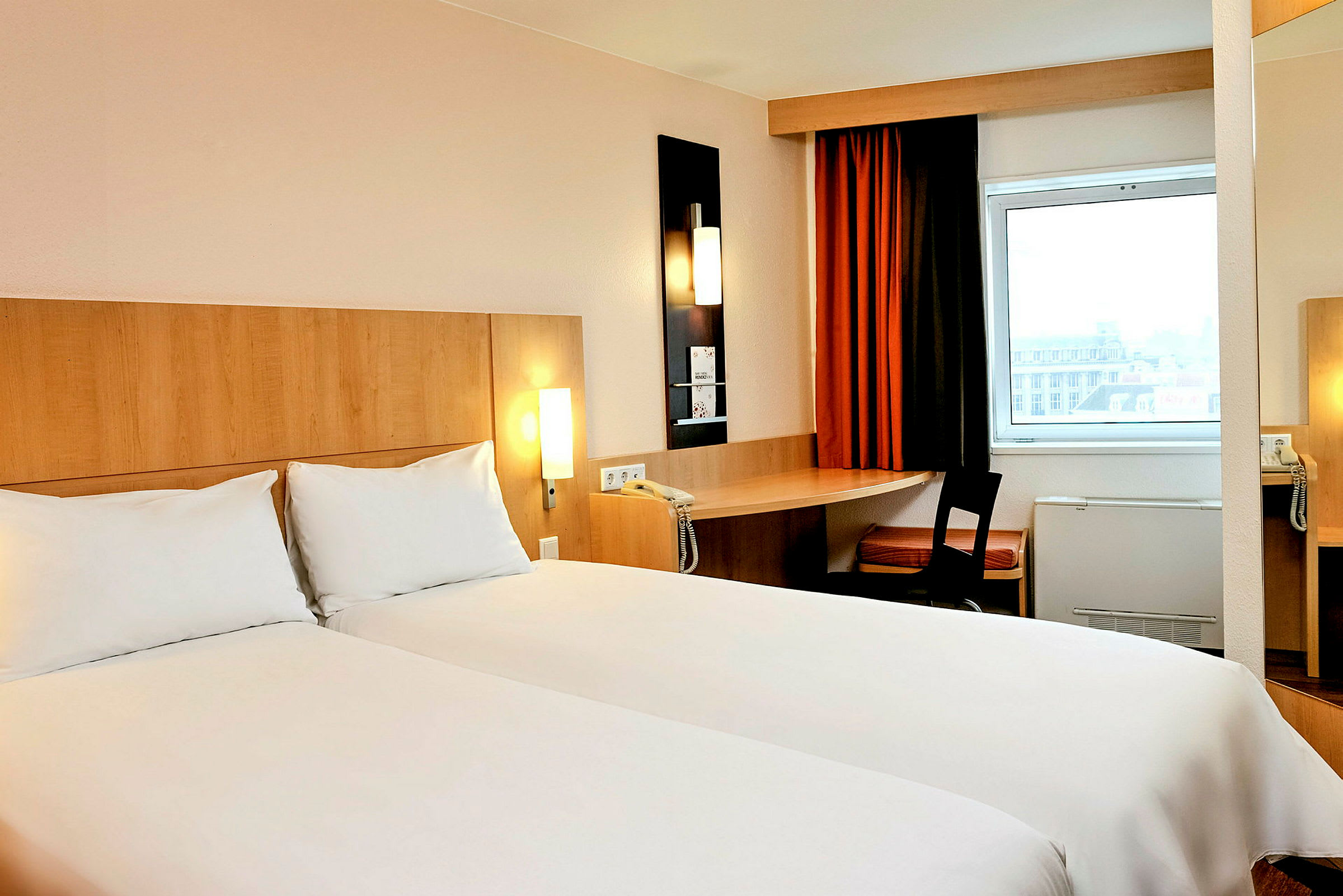 Ett hotellrum med två enkelsängar, ett skrivbord med stol och ett fönster. (AI-genererad text)