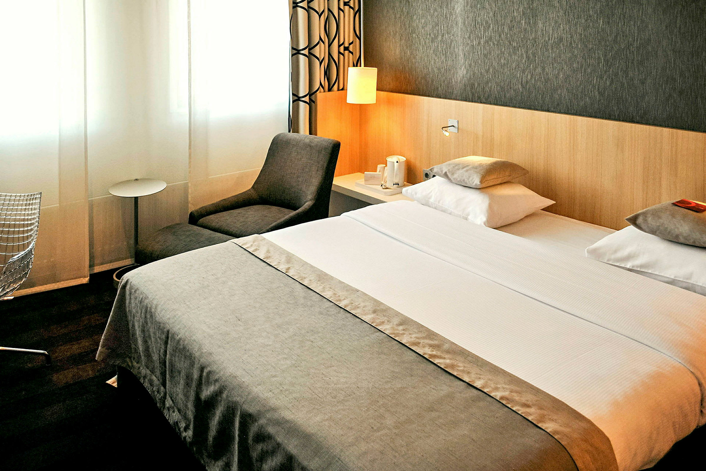 Hotellrum med dubbelsäng, fåtölj och sidobord. (AI-genererad text)