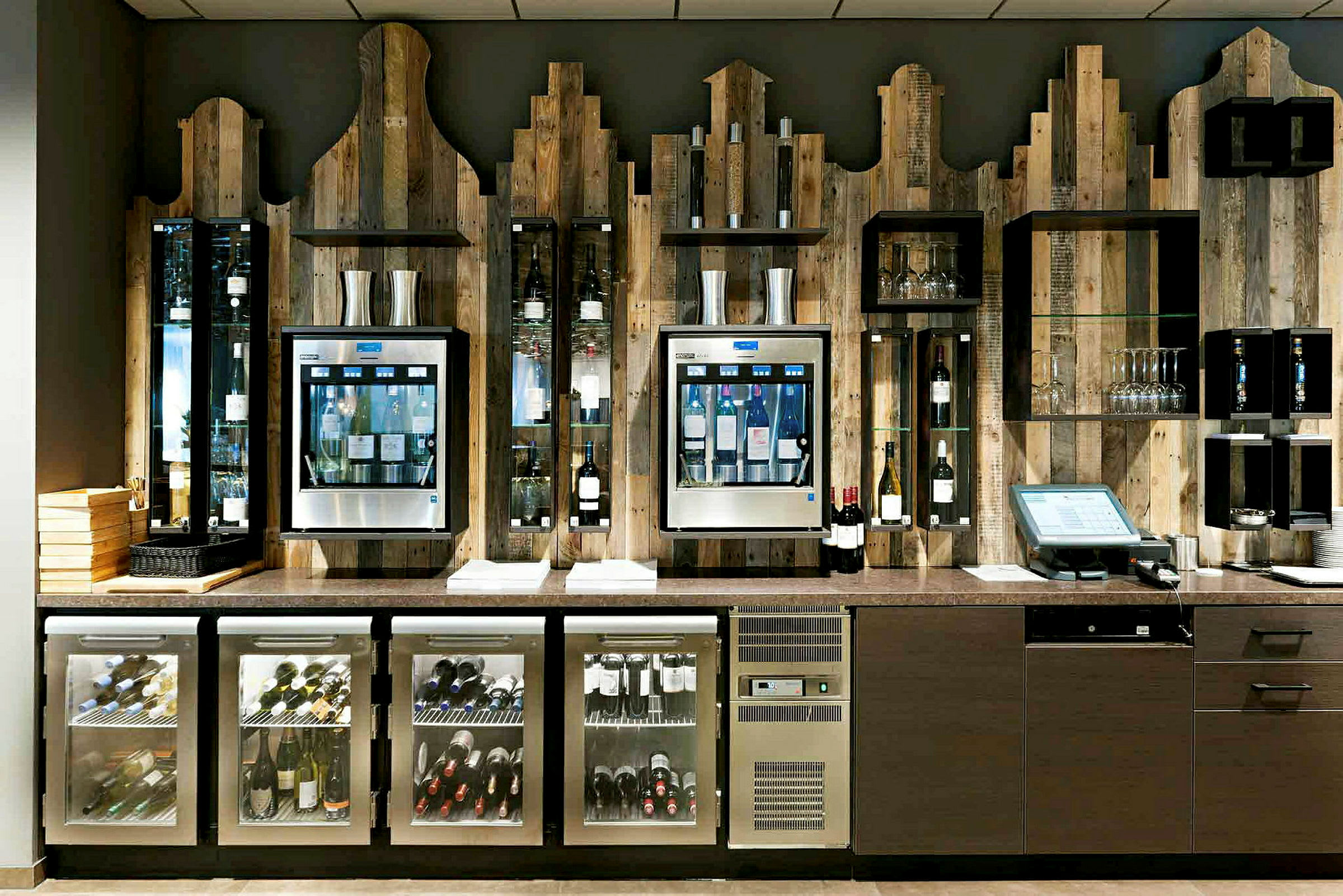 En vinbar med flaskor och glas är placerad mot en trävägg. (AI-genererad text)