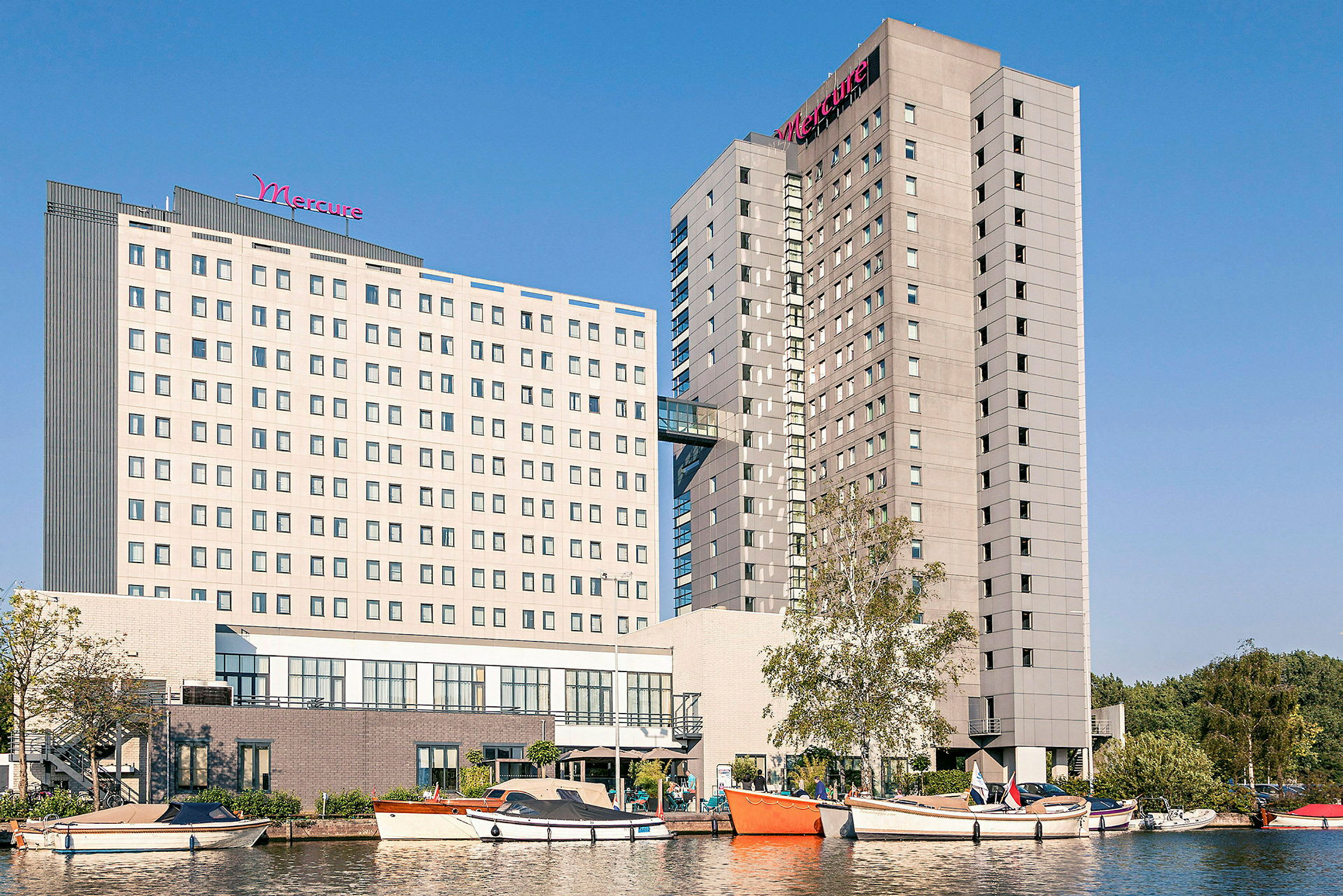 Bild av hotellbyggnader med båtar och vatten i förgrunden. (AI-genererad text)