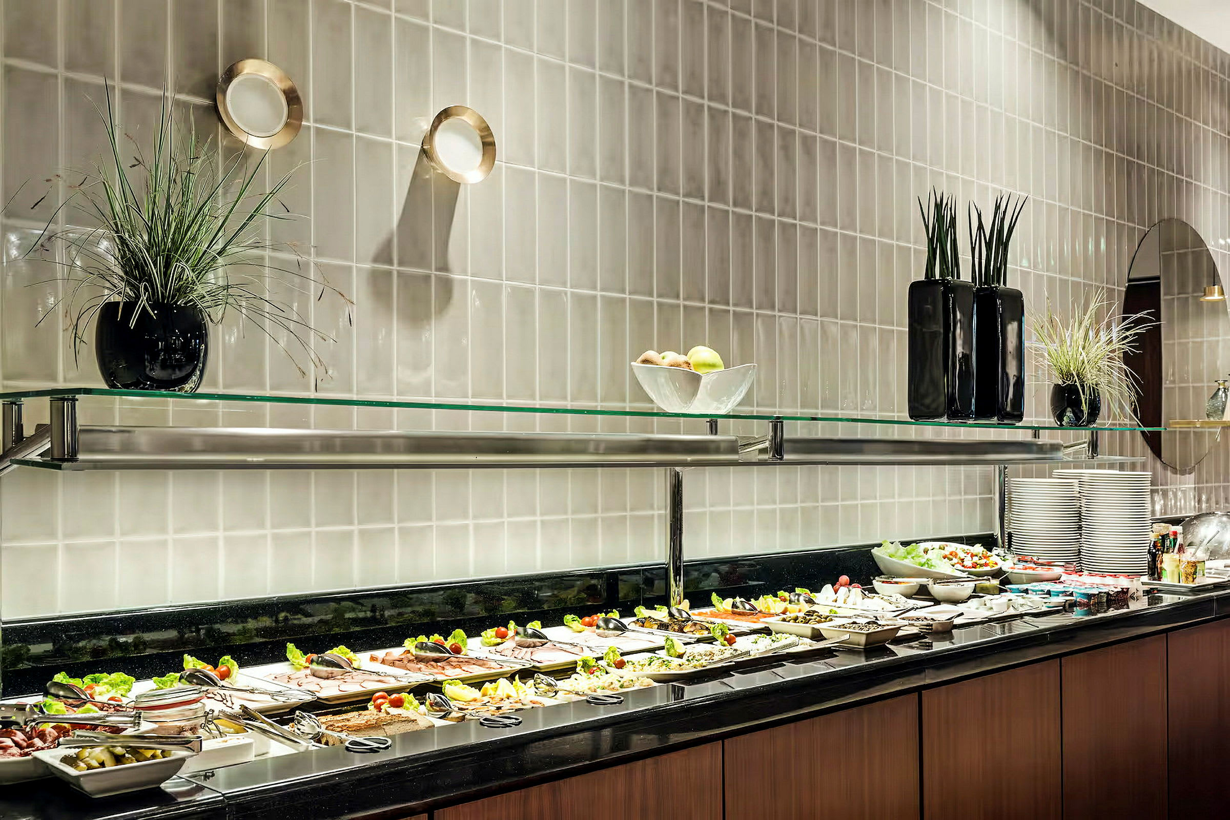 Bild av en bufférestaurang med en uppsättning av tallrikar och olika maträtter och tillbehör framställda på en svart yta under en glashylla. (AI-genererad text)