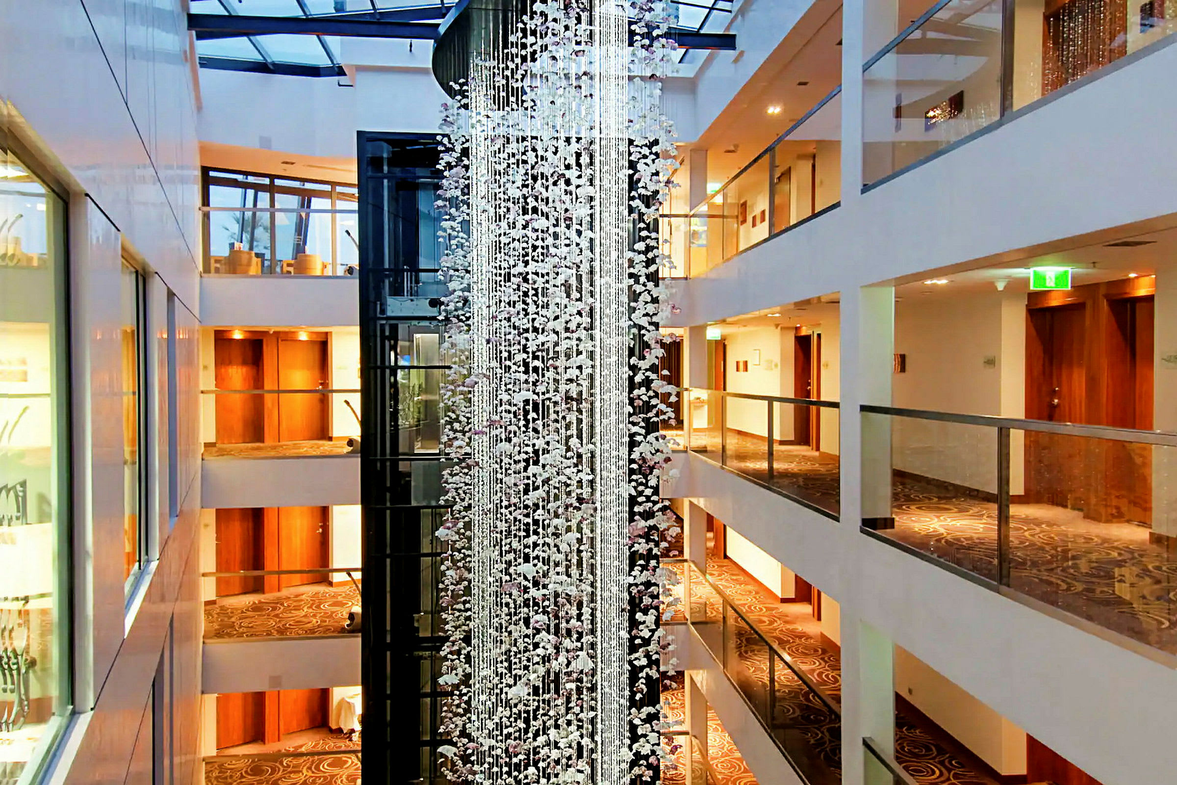 En hotellfoajé med flera våningar, dekorerad med en glashängande installation och varma ljusa färger. (AI-genererad text)