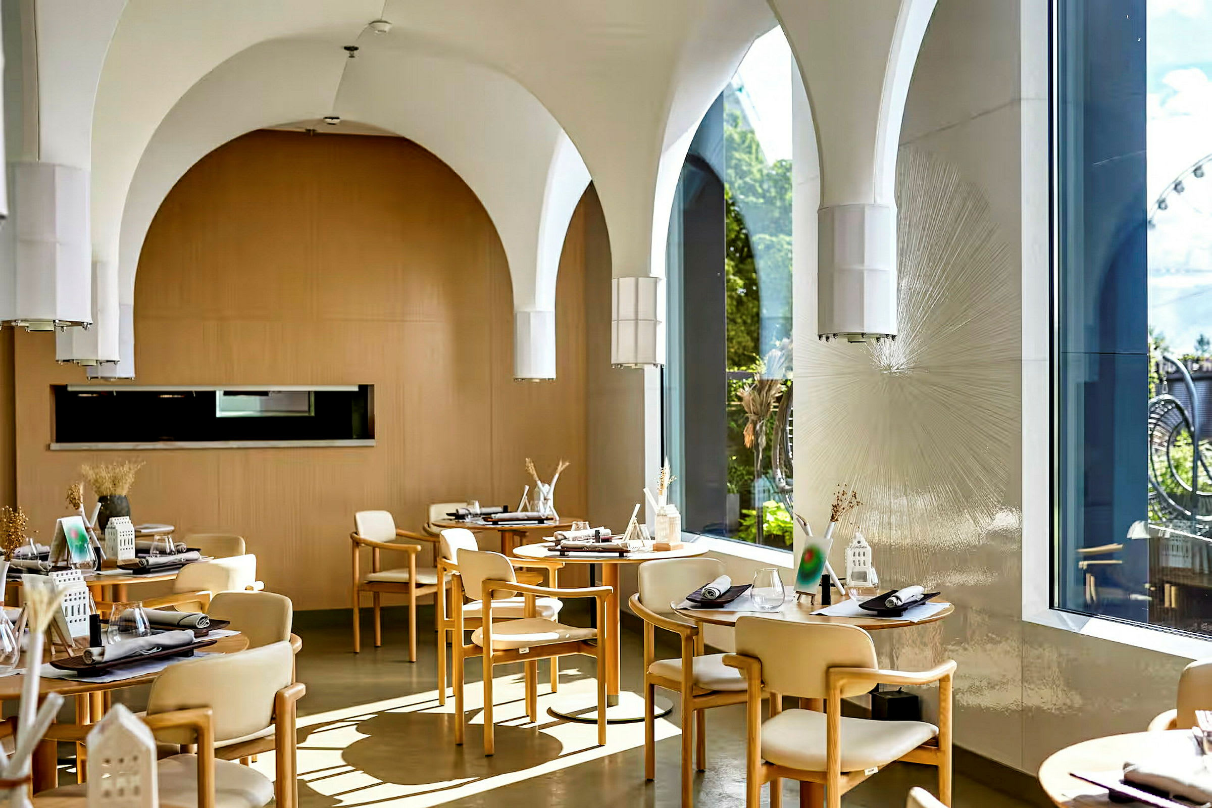 Ett elegant inrett kafé eller restaurang med bågformade tak, trästolar, och dukade bord. (AI-genererad text)