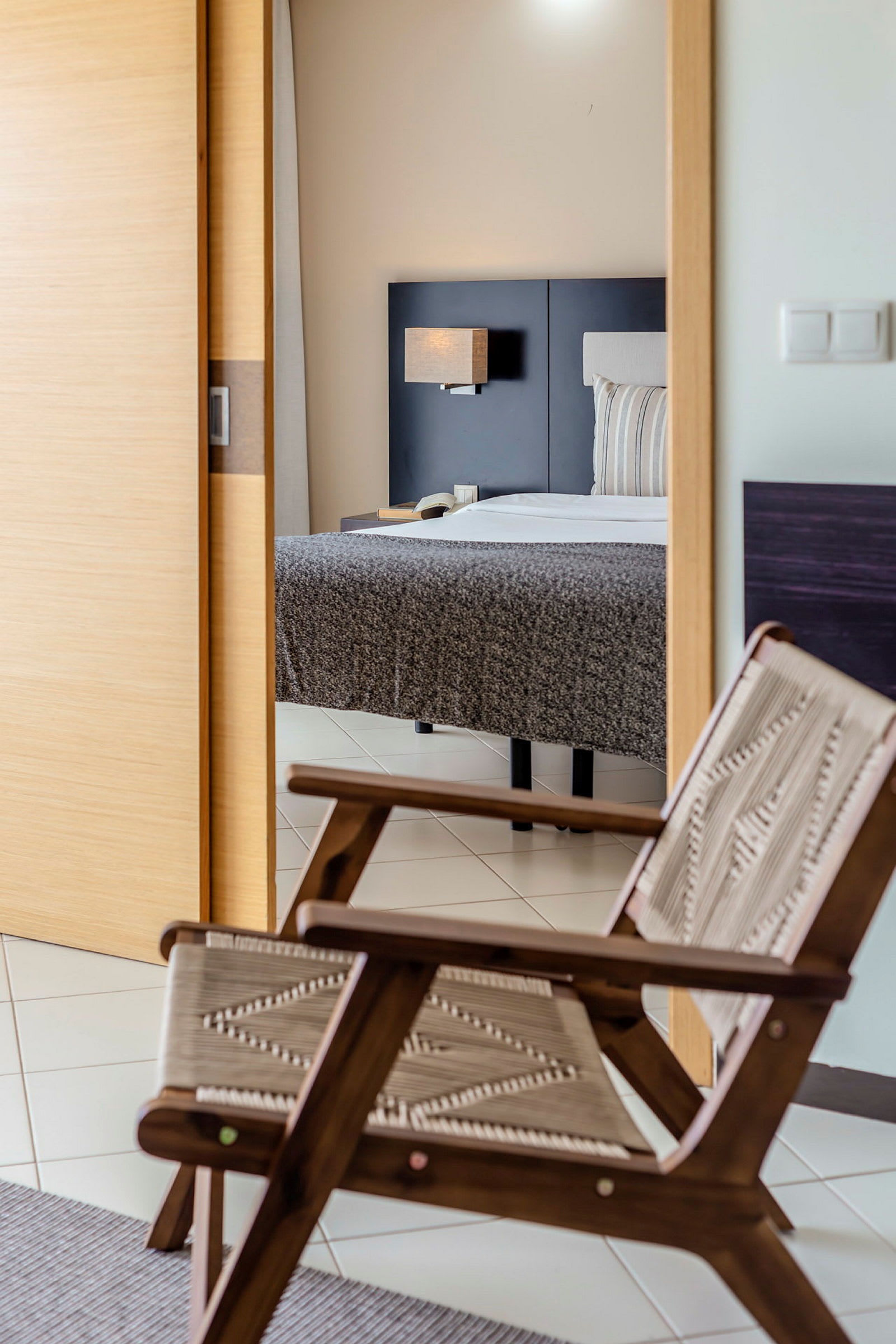 Ett hotellrum med en stol och en säng i bakgrunden. (AI-genererad text)