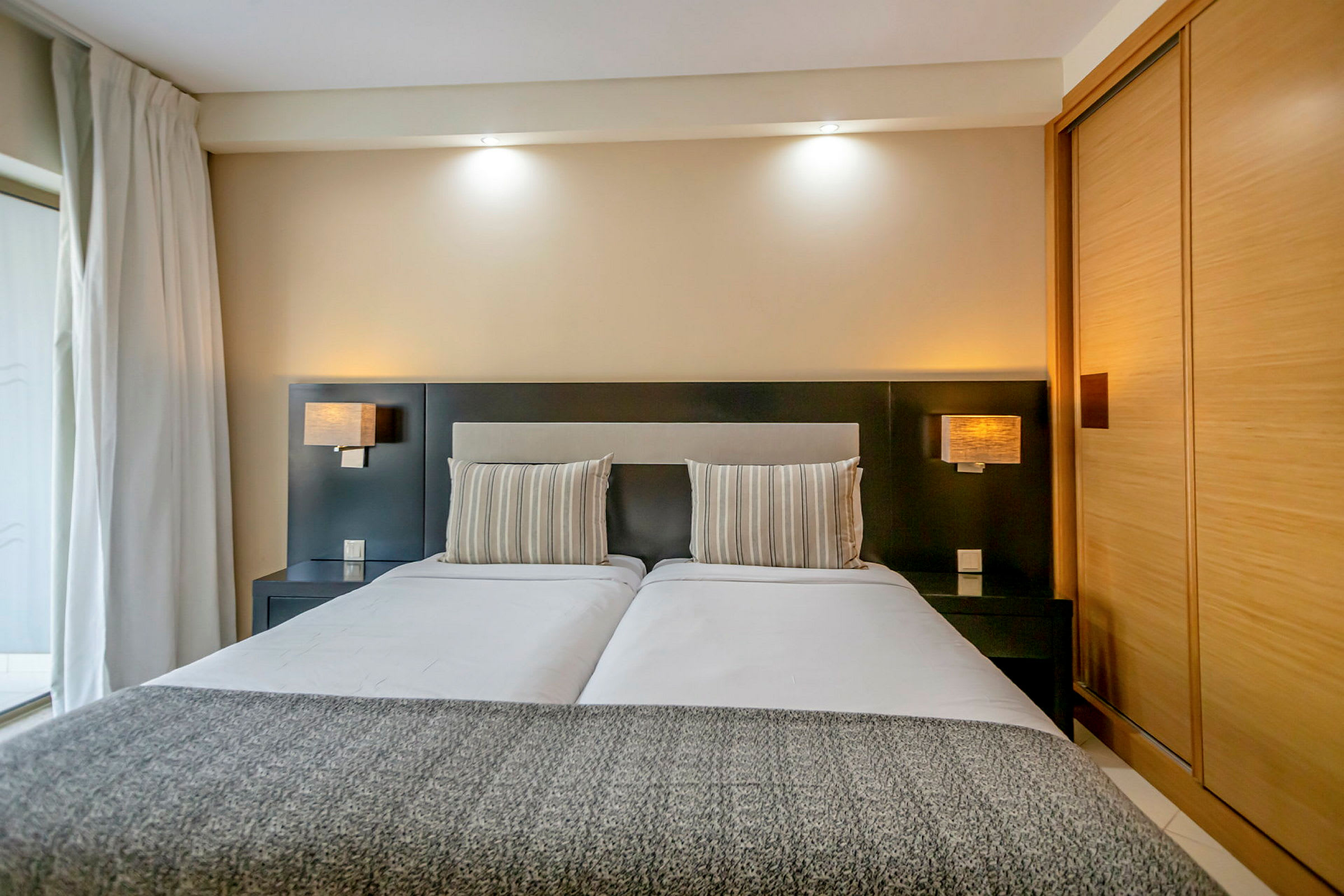 Bild på ett modernt hotellrum med en dubbelsäng, randiga kuddar och stilren inredning. (AI-genererad text)