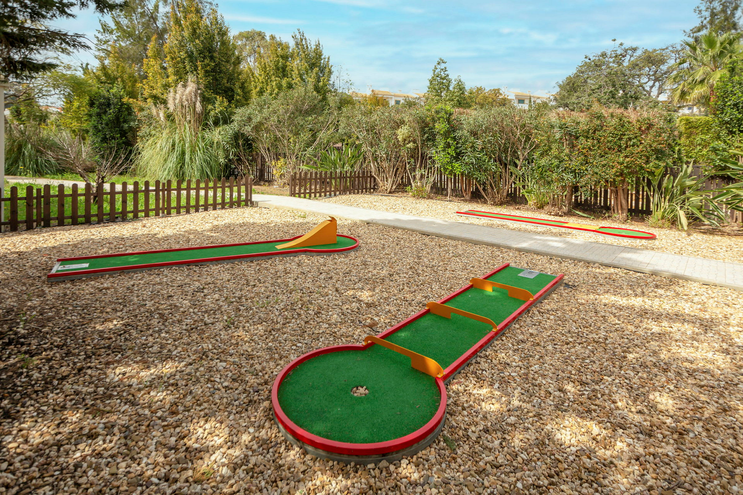 Minigolfbanor omgivna av staket och grönska. (AI-genererad text)