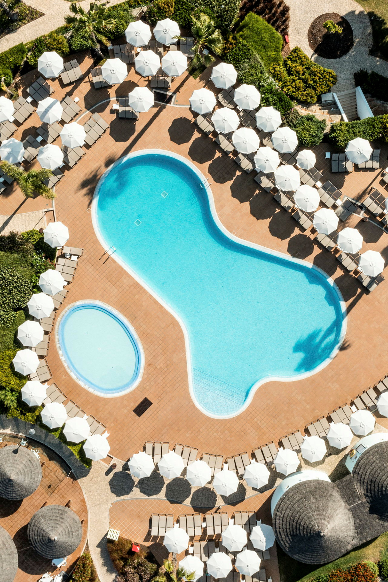 Flygbild på ett poolområde med solstolar och parasoller. (AI-genererad text)
