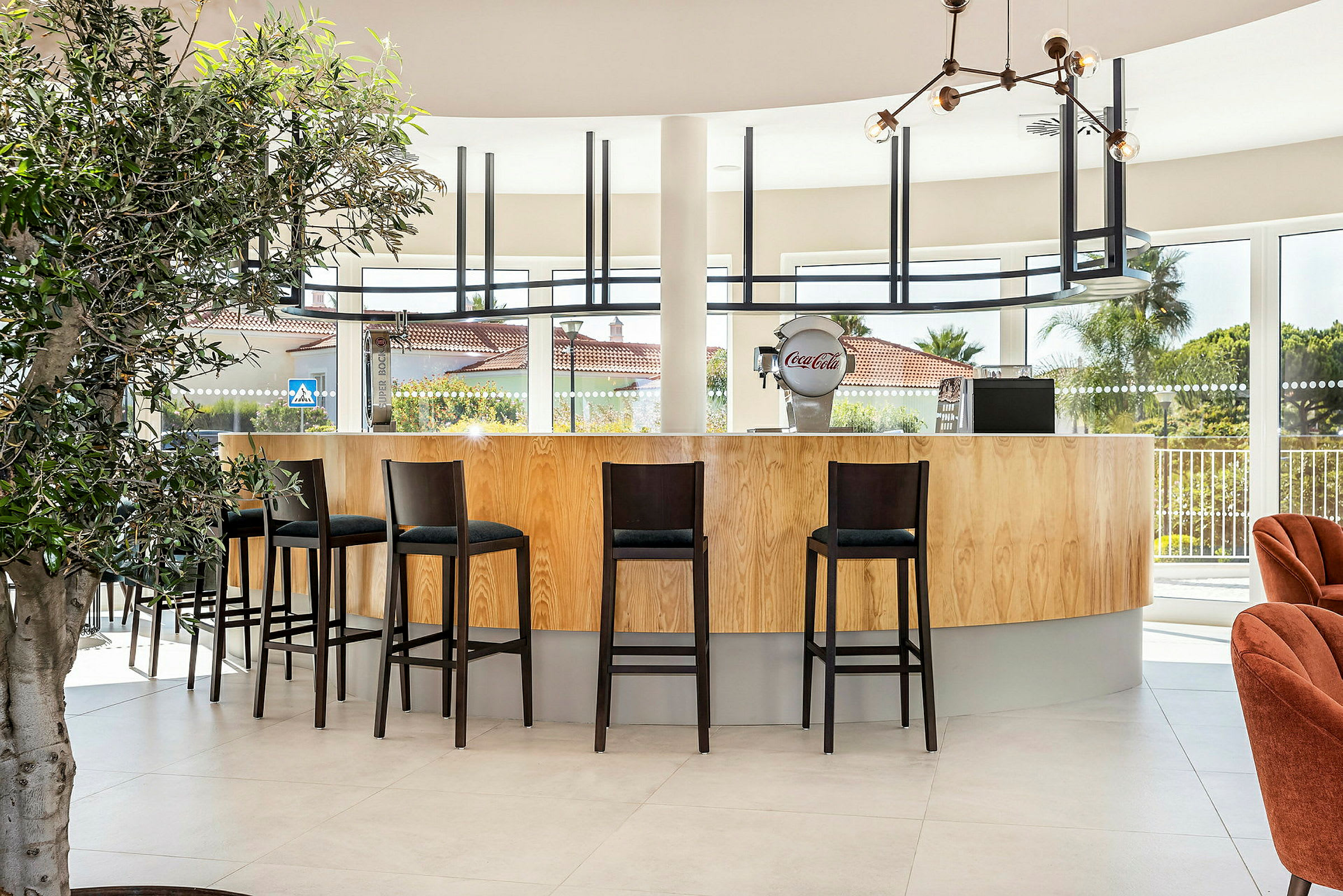 En modern bar med höga stolar och stora fönster. (AI-genererad text)