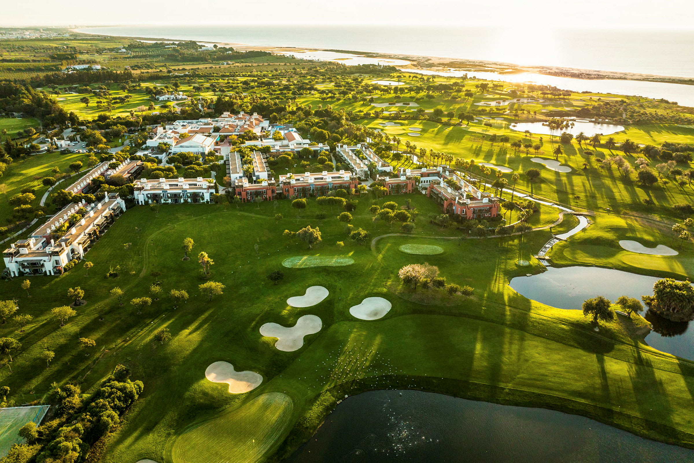 Luftbild av grönområden med byggnader och golfbanor vid havet. (AI-genererad text)