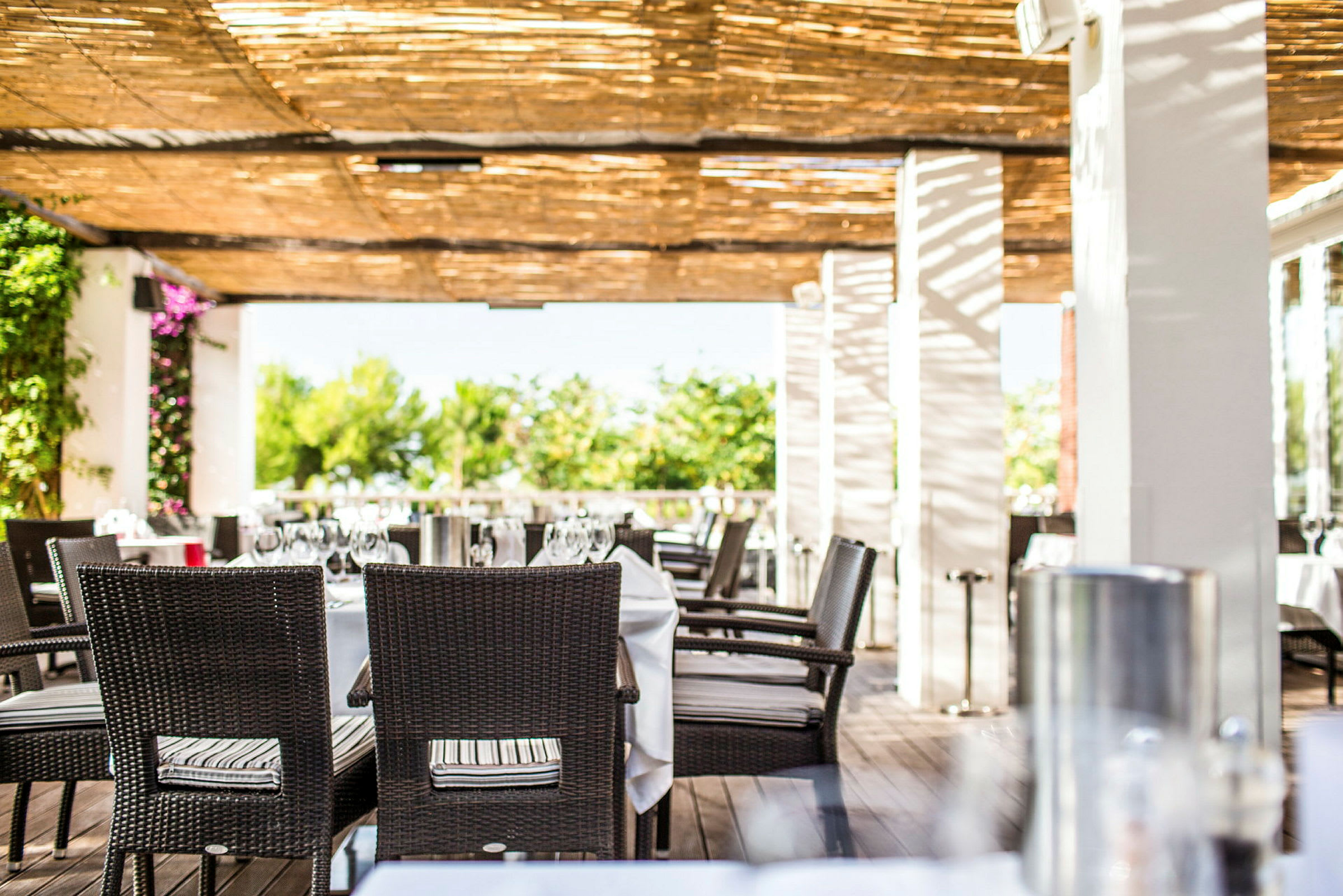 En utomhusrestaurang med dukade bord under en pergola. (AI-genererad text)