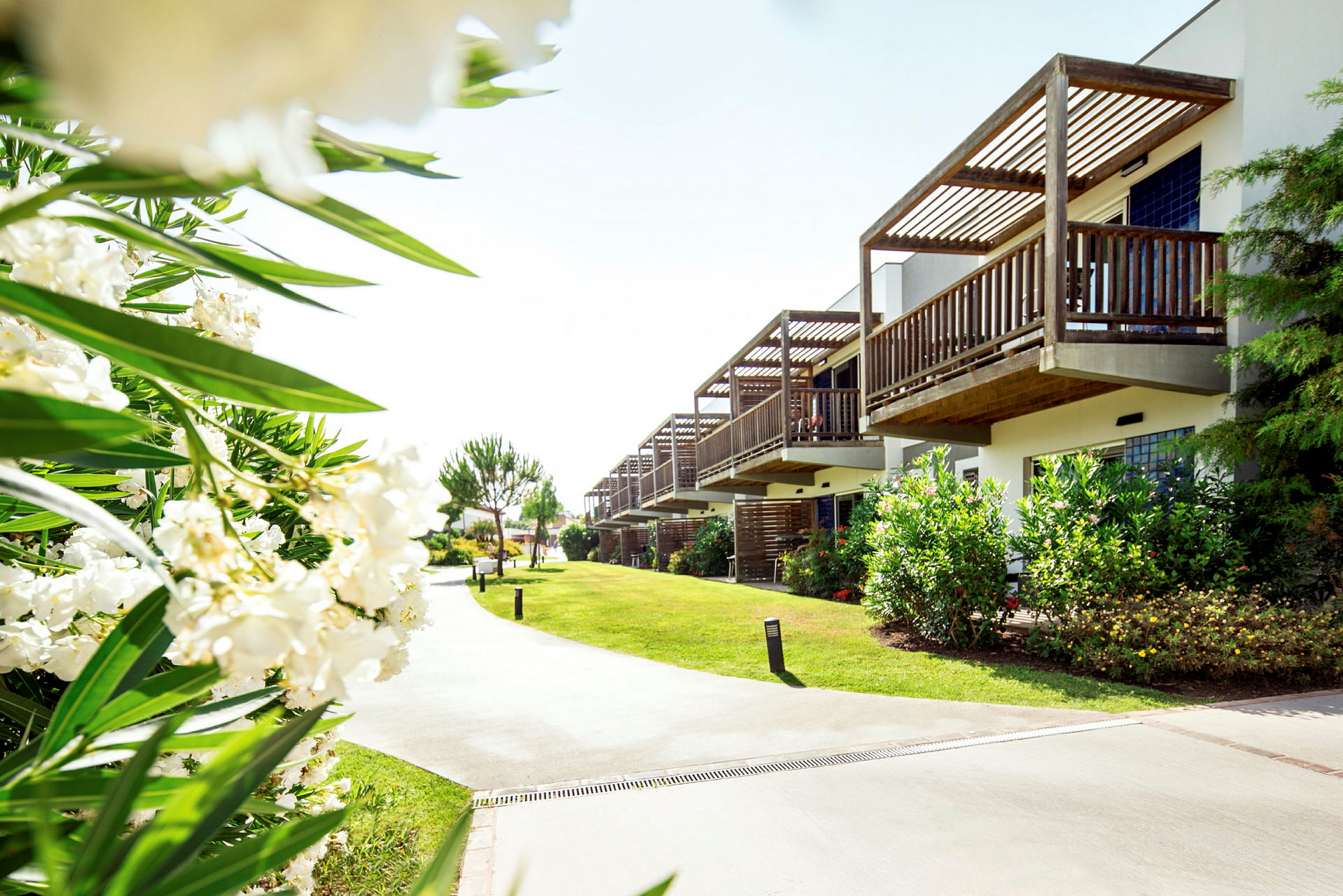 Utomhusmiljö med flera byggnader, grönområden och blommande buskar. (AI-genererad text)