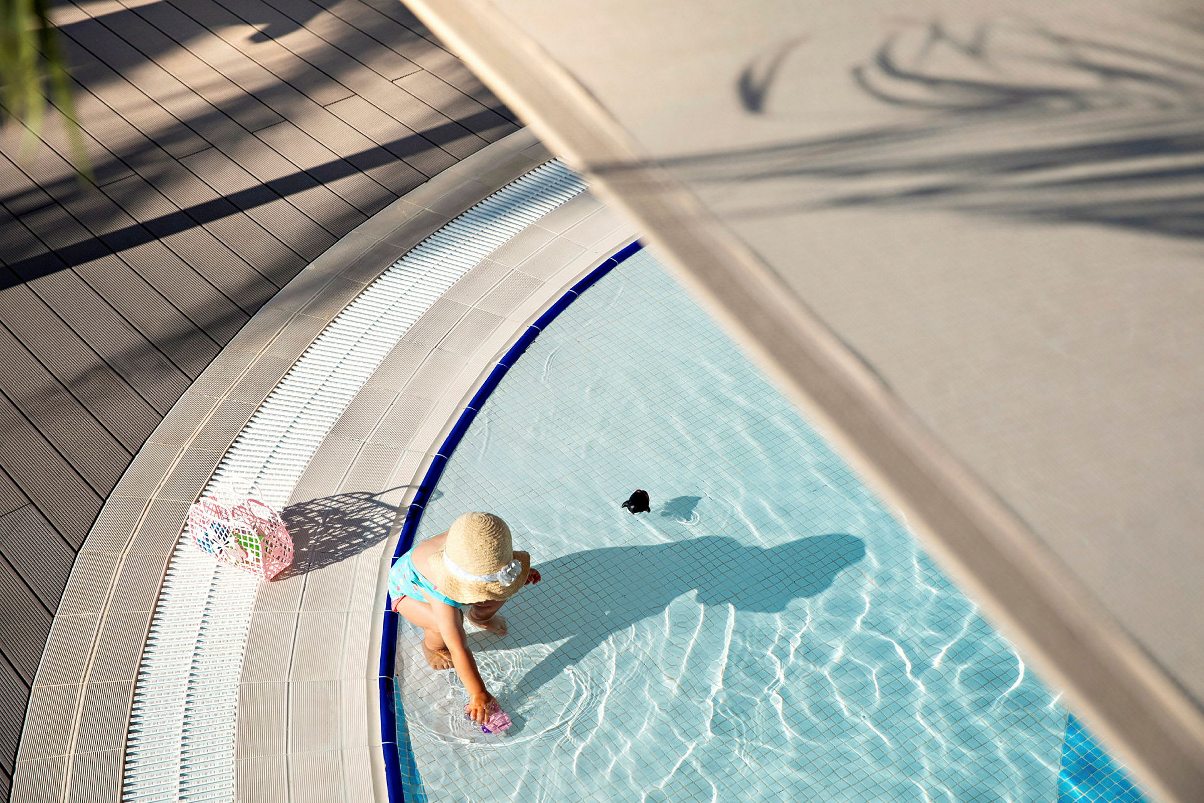 Ett barn i en hatt leker vid kanten av en pool. (AI-genererad text)