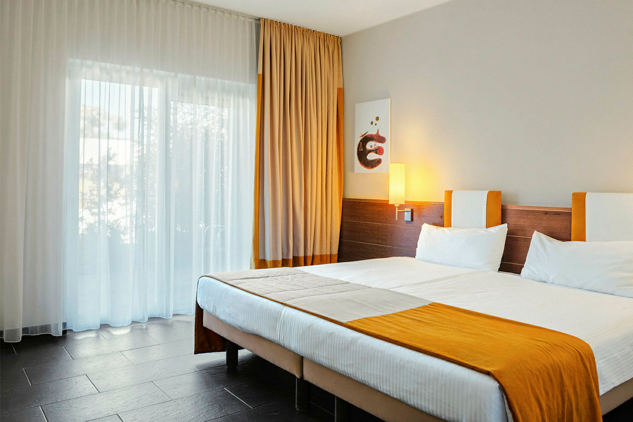 Ett hotellrum med en dubbelsäng och orange detaljer. (AI-genererad text)