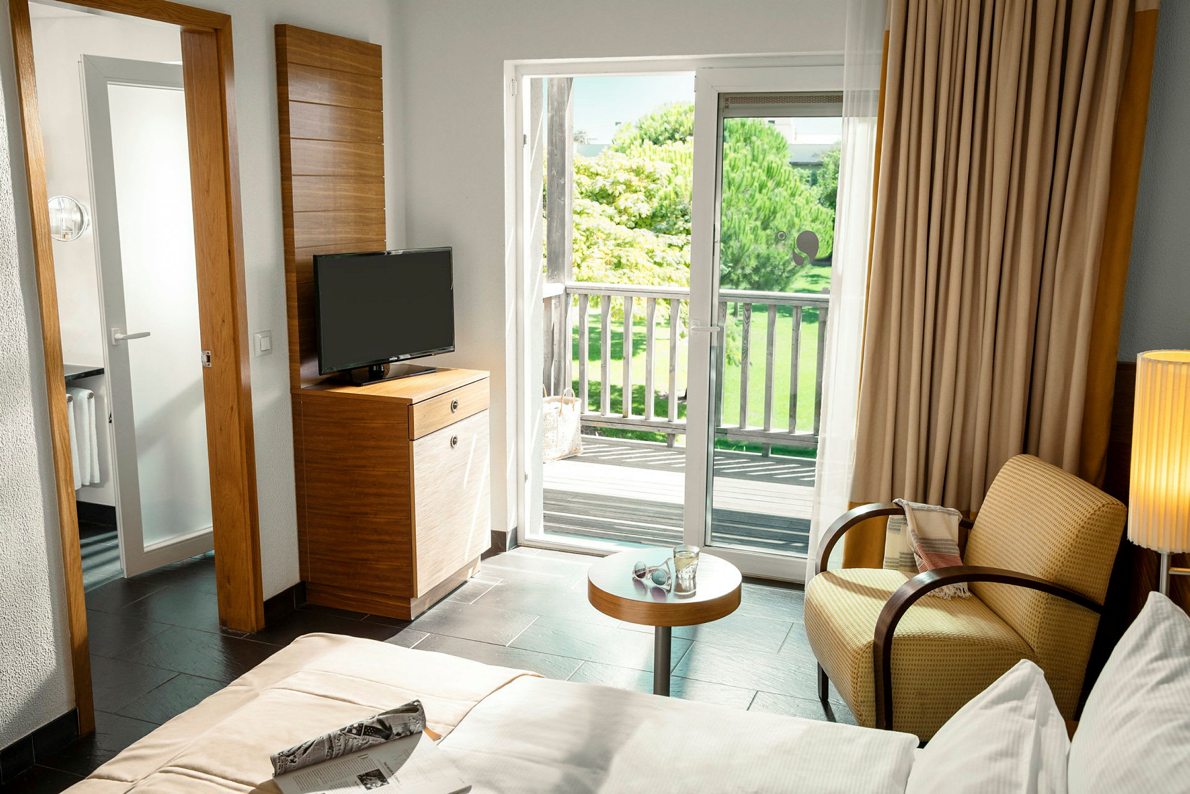Ett hotellrum med en balkong och vy över grönska utanför. (AI-genererad text)
