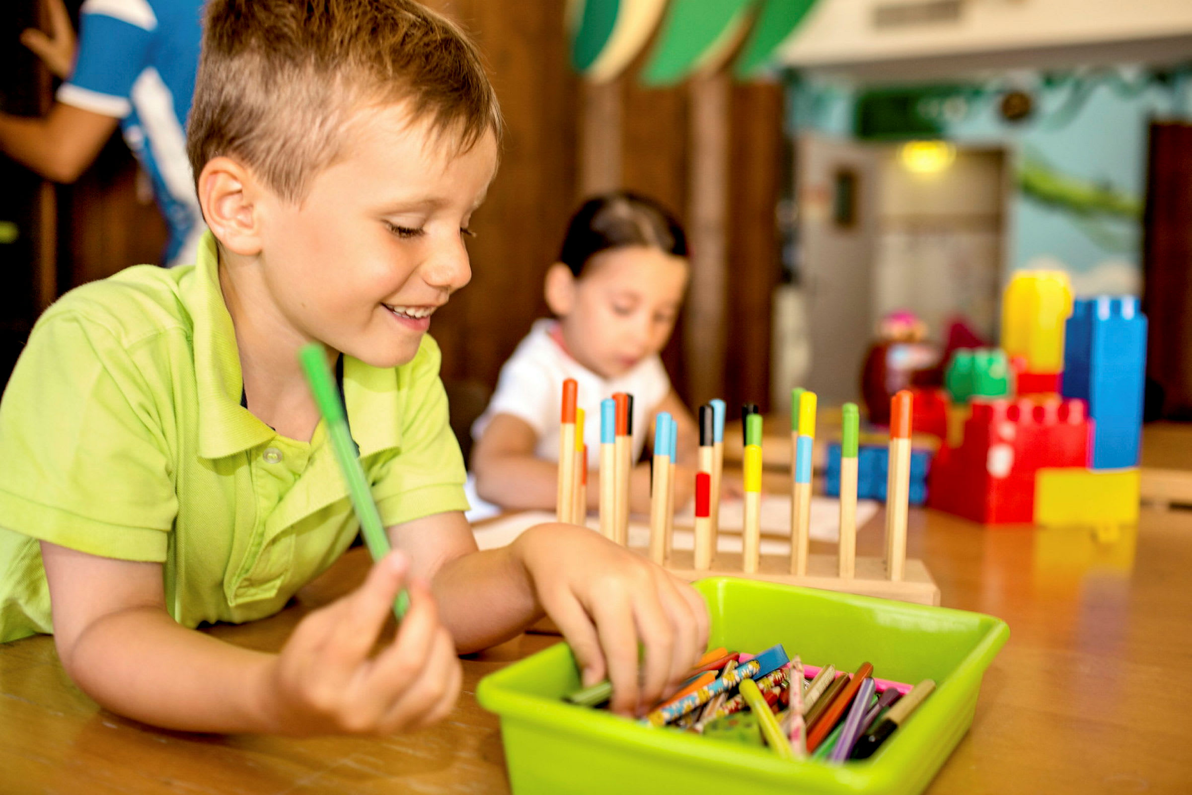 Ett barn sitter vid ett bord med färgglada kritor och pedagogiska leksaker. (AI-genererad text)