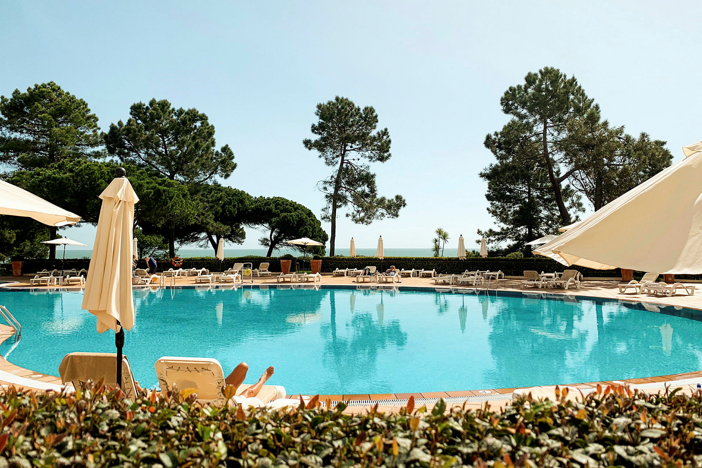 Utomhuspool vid ett hotell med solstolar och parasoller. (AI-genererad text)