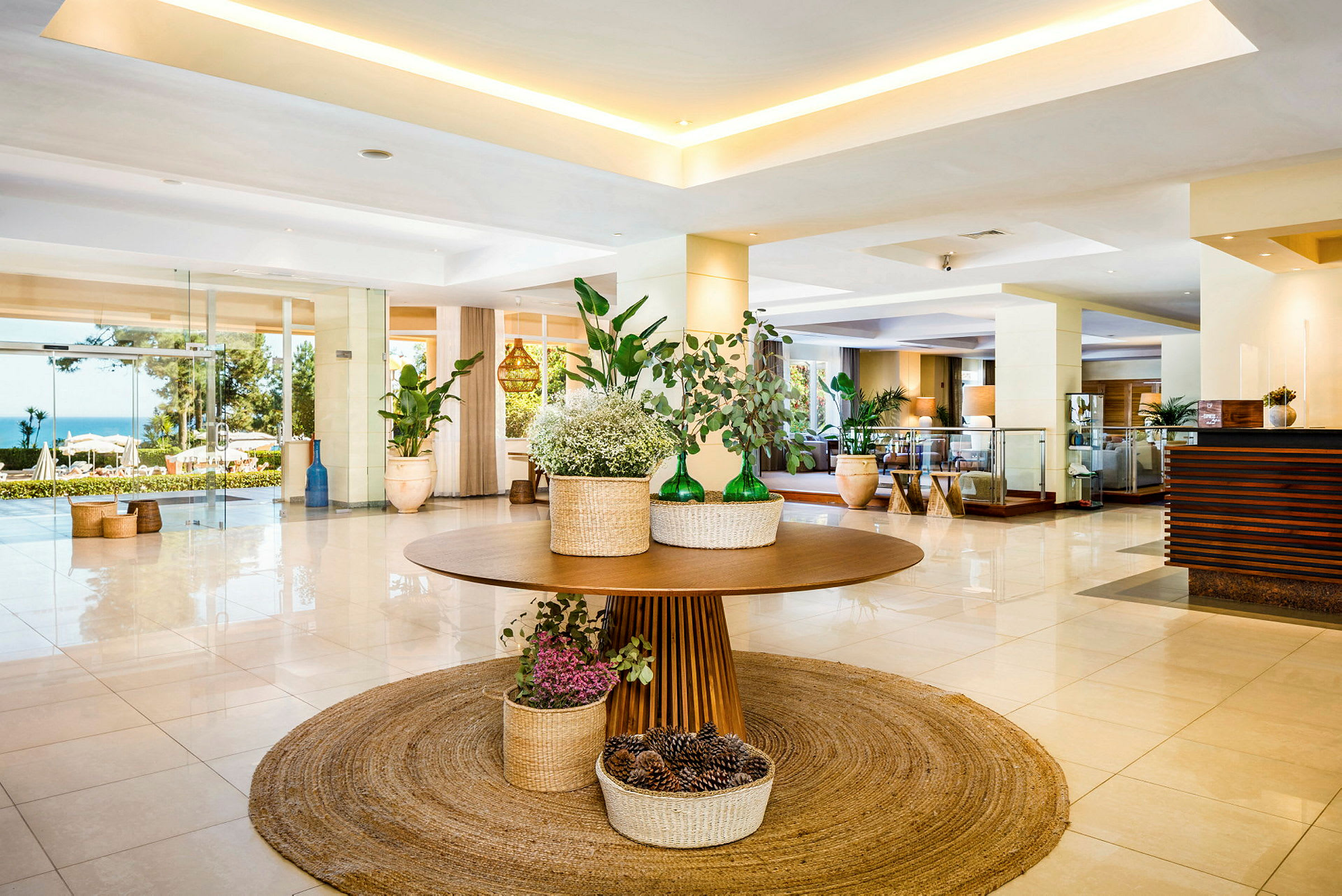 Hotellobby med ett dekorerat bord med växter och korgar på en rund matta. (AI-genererad text)
