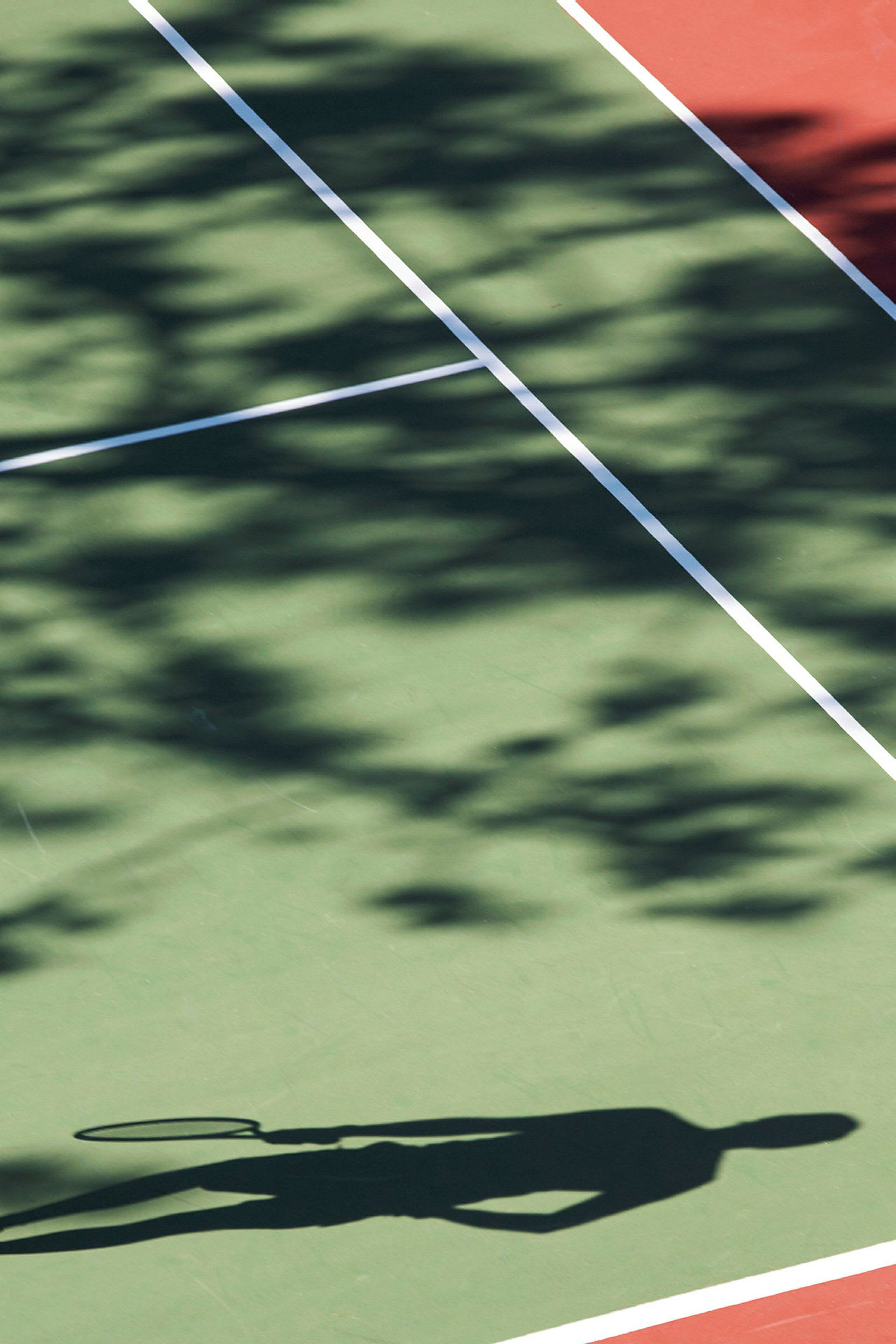 Skugga av en person med tennisracket på en tennisplan. (AI-genererad text)