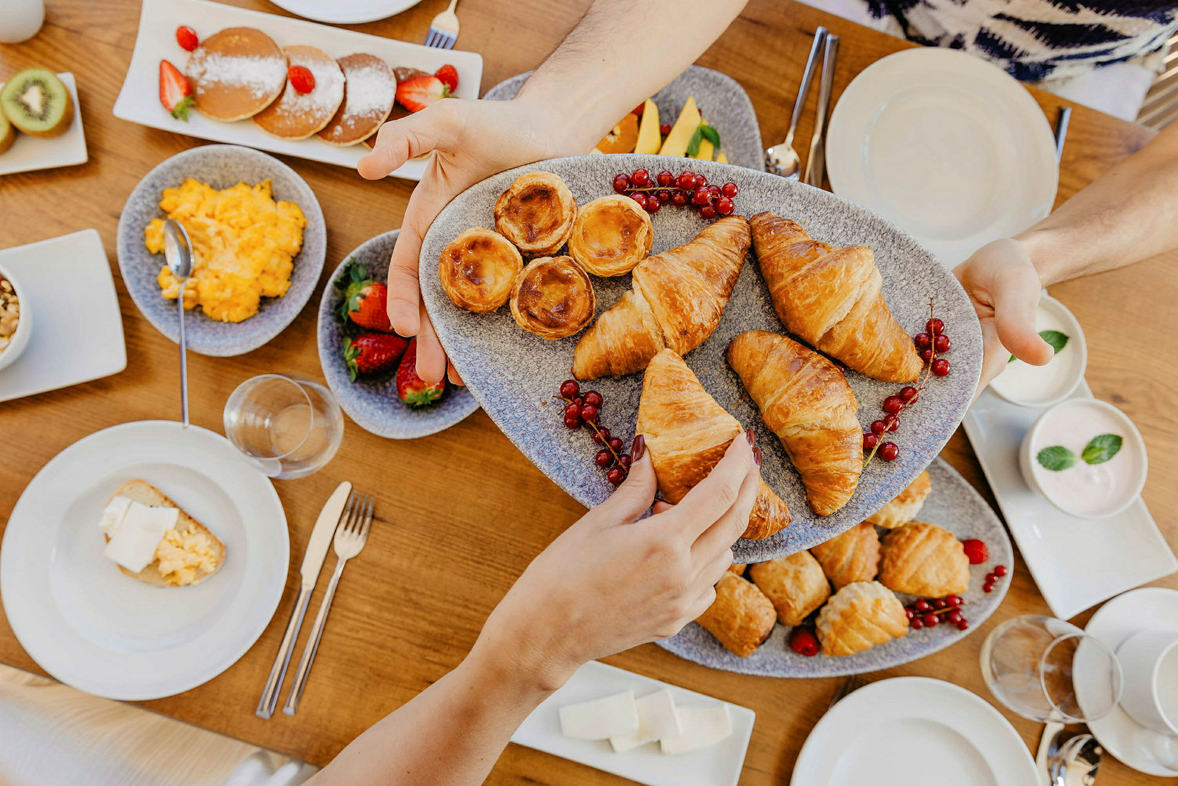 En frukost med olika bakverk, frukter och andra maträtter serverade på ett bord. (AI-genererad text)