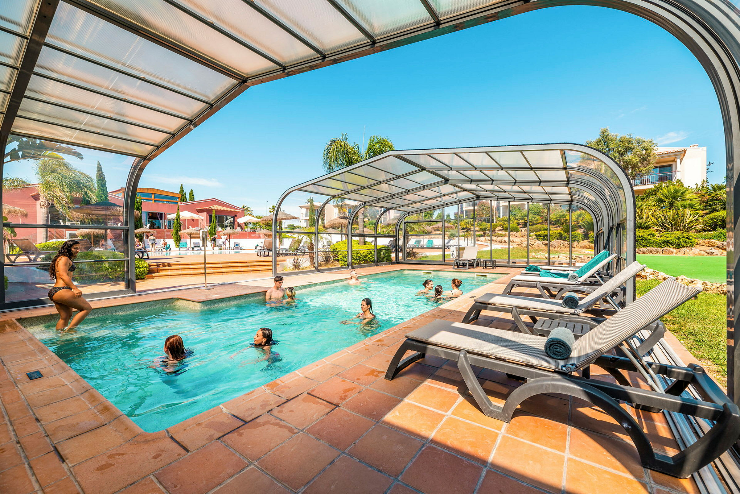 En pool med glastak och solstolar bredvid. (AI-genererad text)