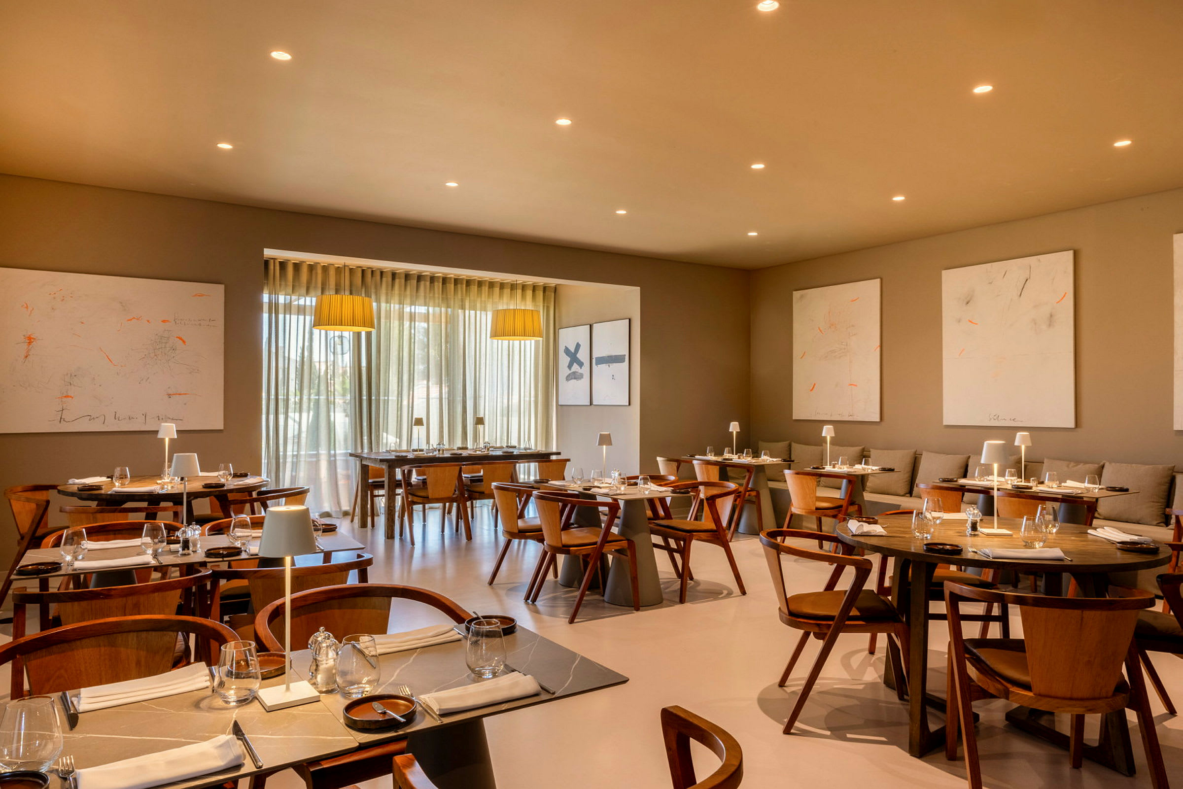 En modern restaurang med träbord och stolar, dekorativ belysning och konstverk på väggen. (AI-genererad text)