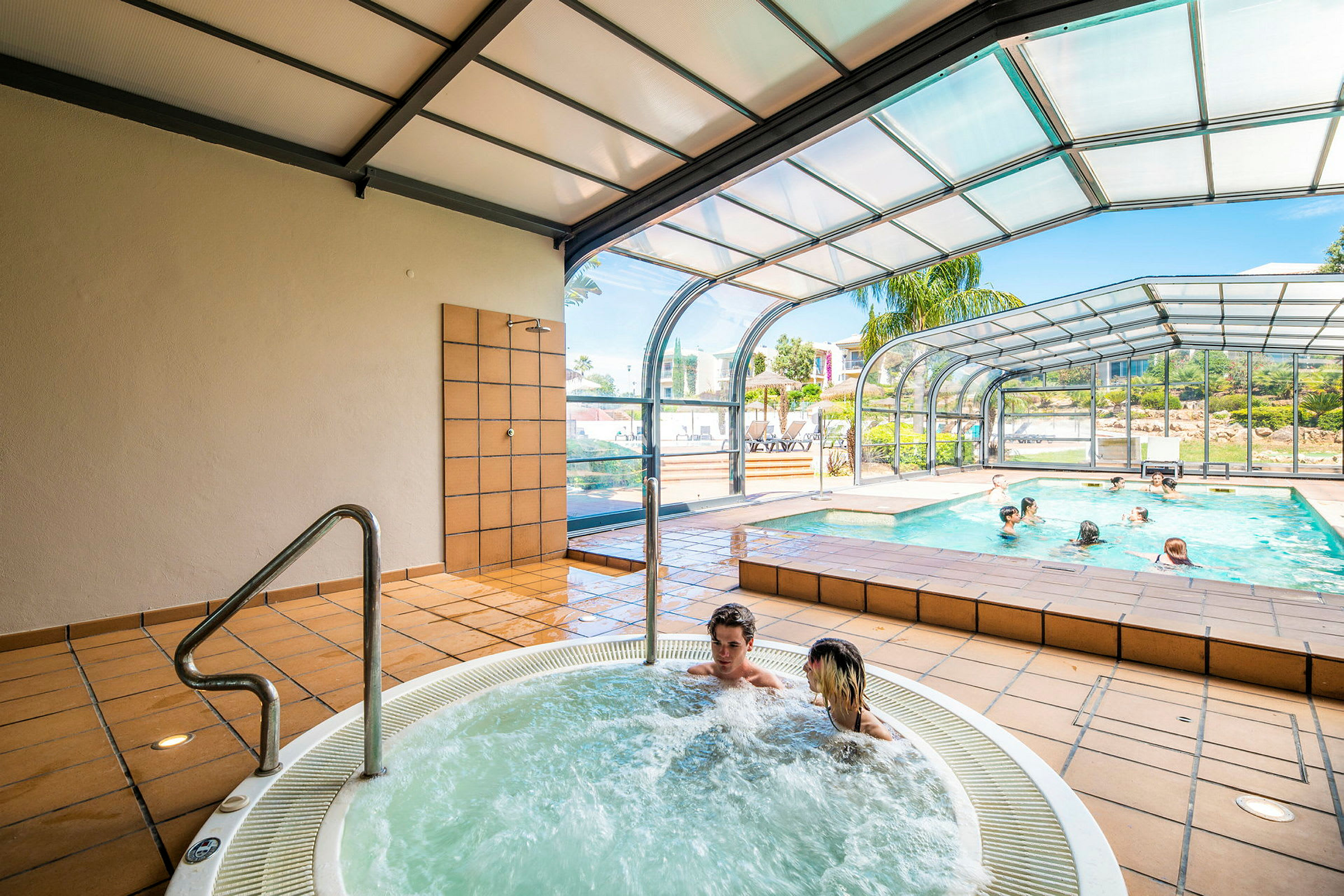 Inomhuspoolområde med bubbelpool och stora fönster som vetter mot utsidan. (AI-genererad text)
