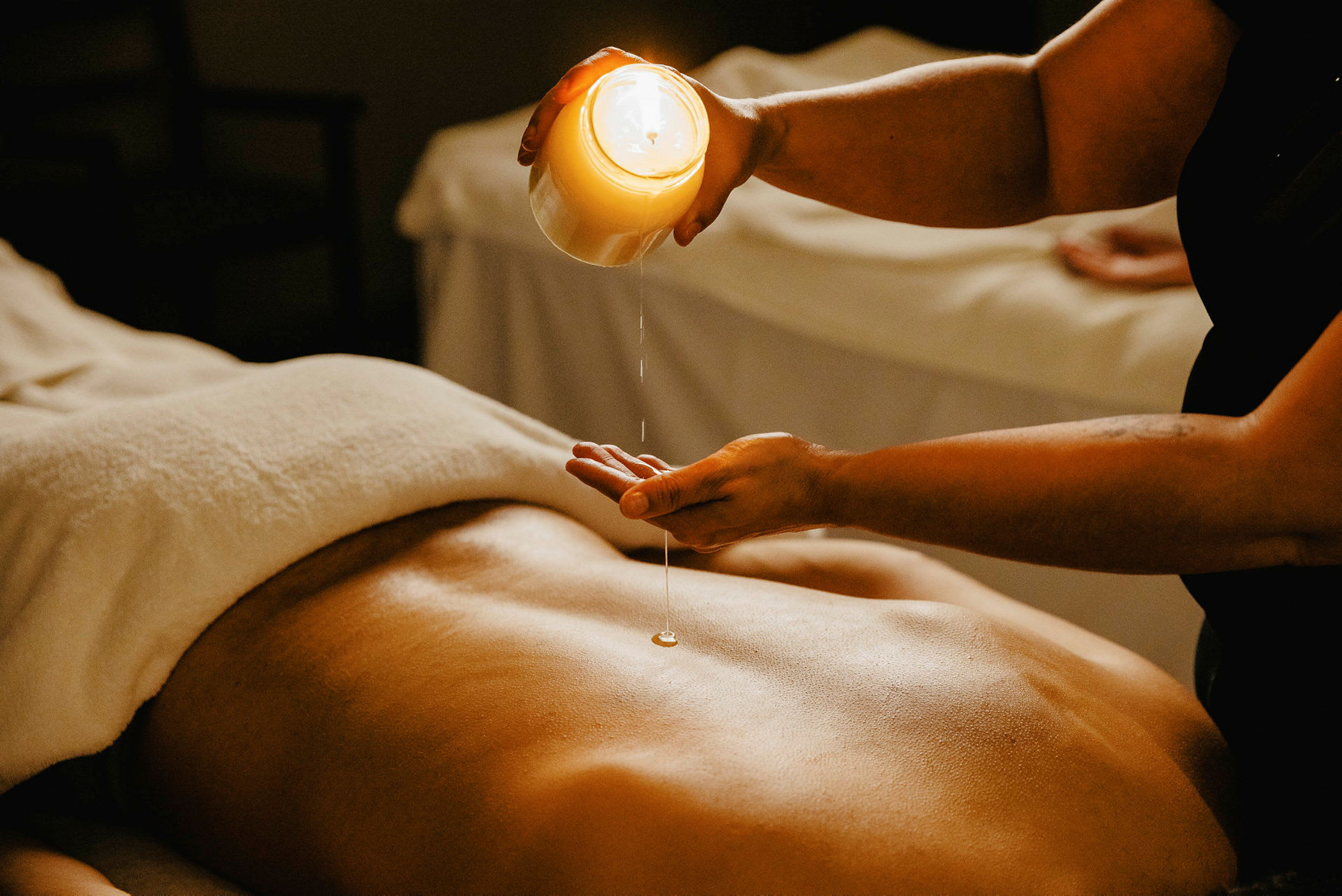 En person förbereder massage med ljusolja på en rygg. (AI-genererad text)