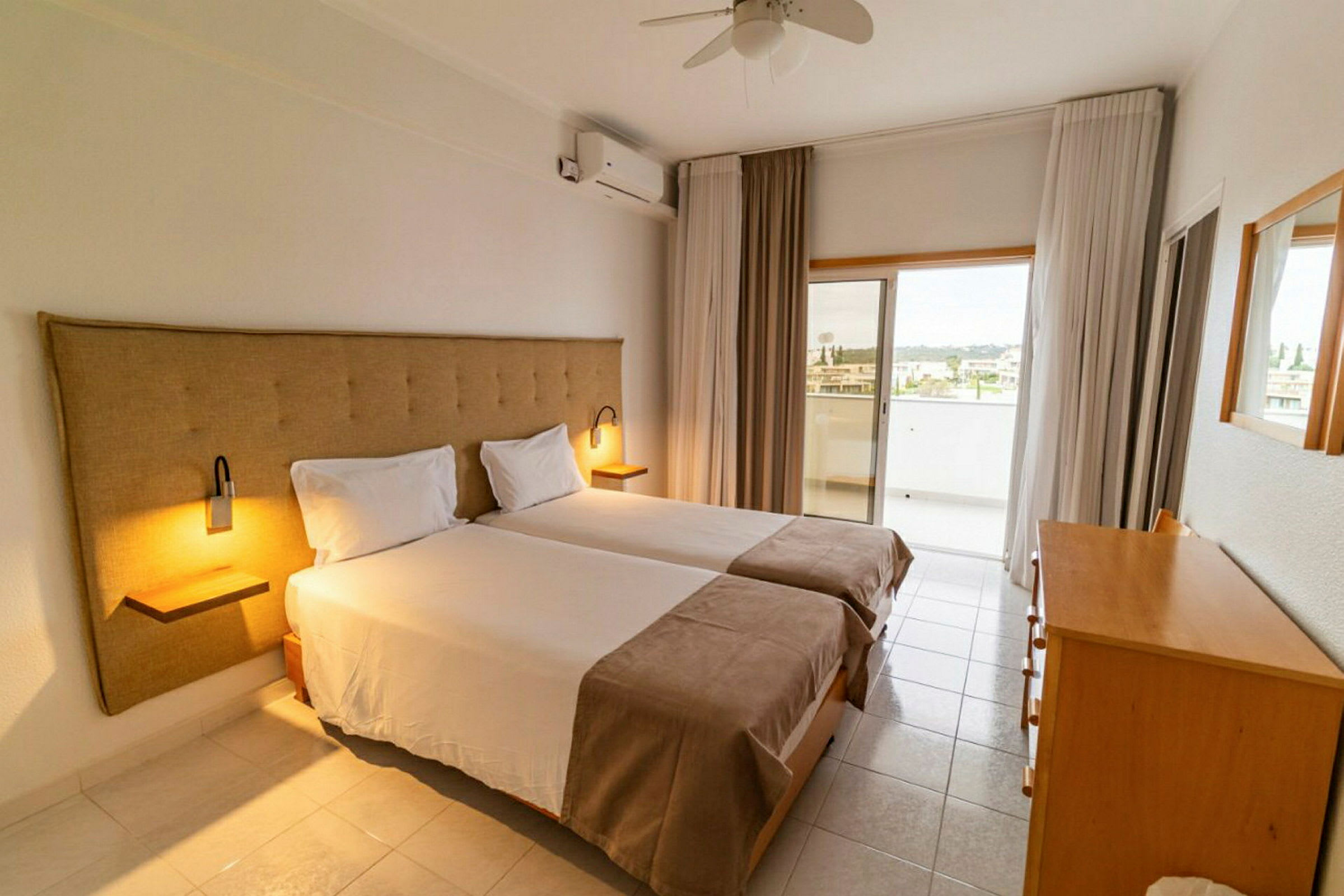 Ett hotellrum med två enkelsängar, en byrå och ett utgång till en balkong. (AI-genererad text)