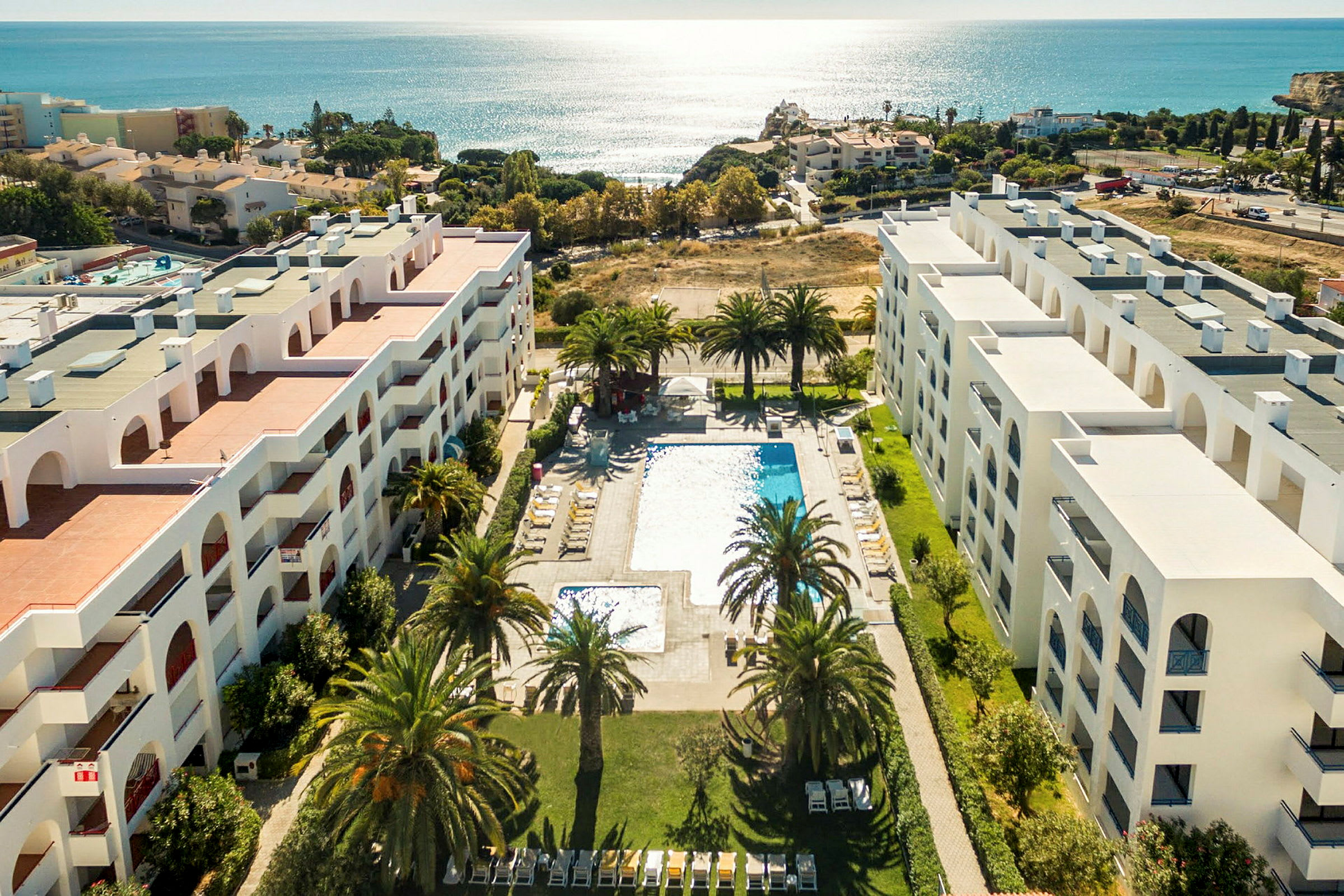 Flygfoto av hotell med poolområde och utsikt över havet. (AI-genererad text)