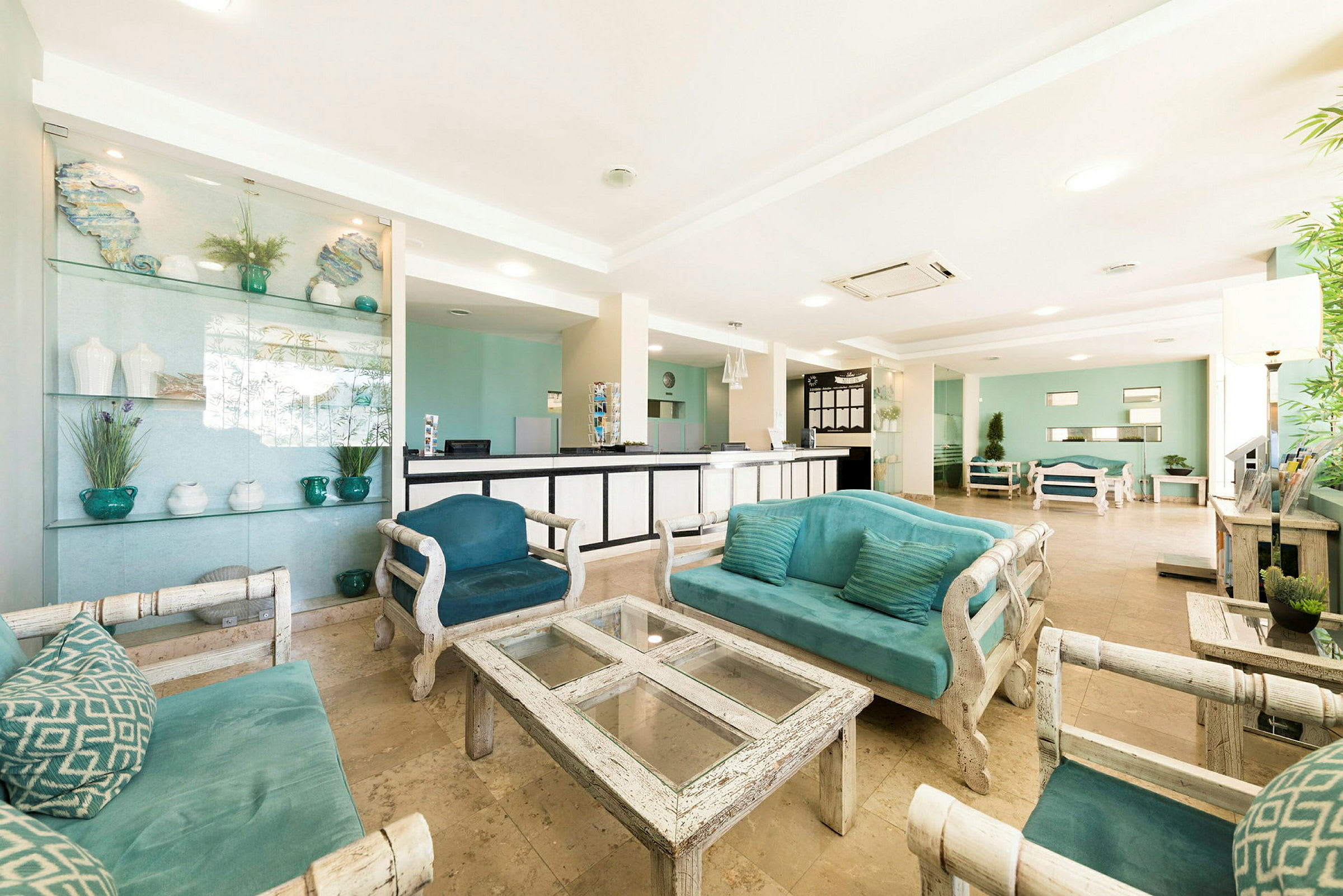 Ljus hotellobby med turkosa soffor, glasbord och receptionsdisk. (AI-genererad text)
