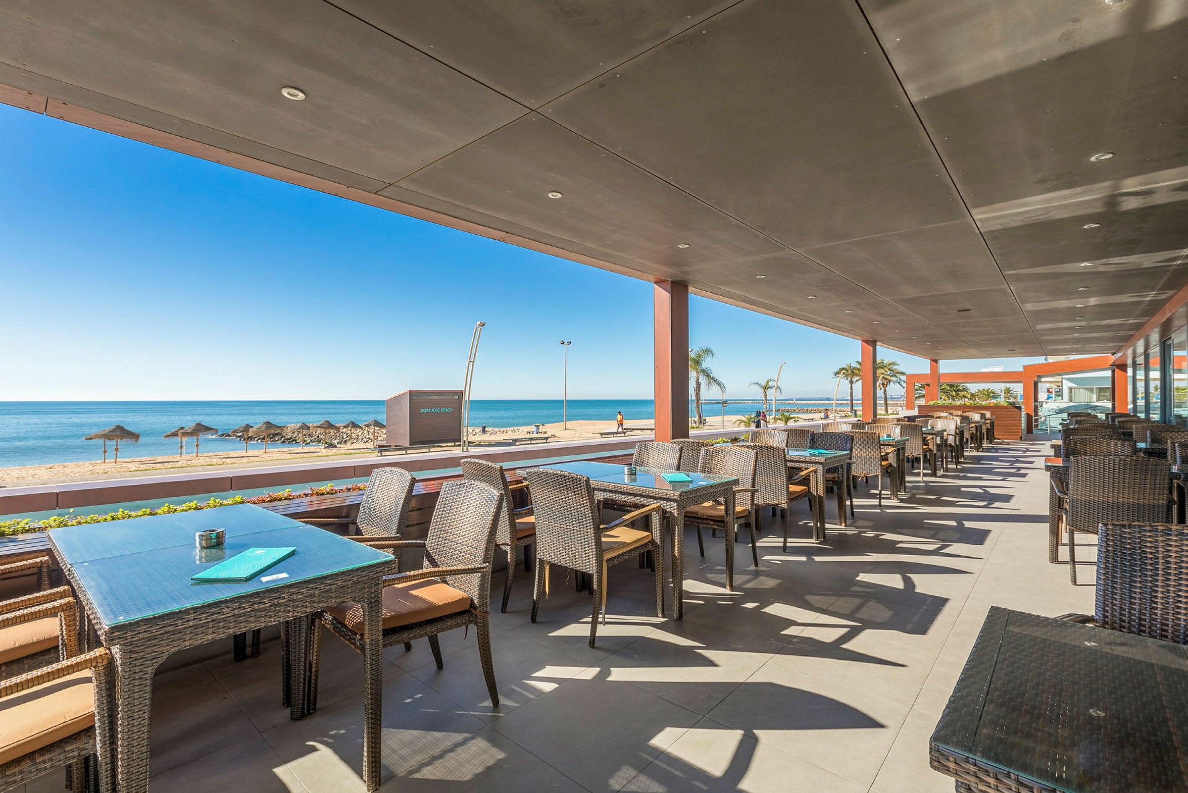 Restaurang med uteservering och utsikt över stranden och havet. (AI-genererad text)