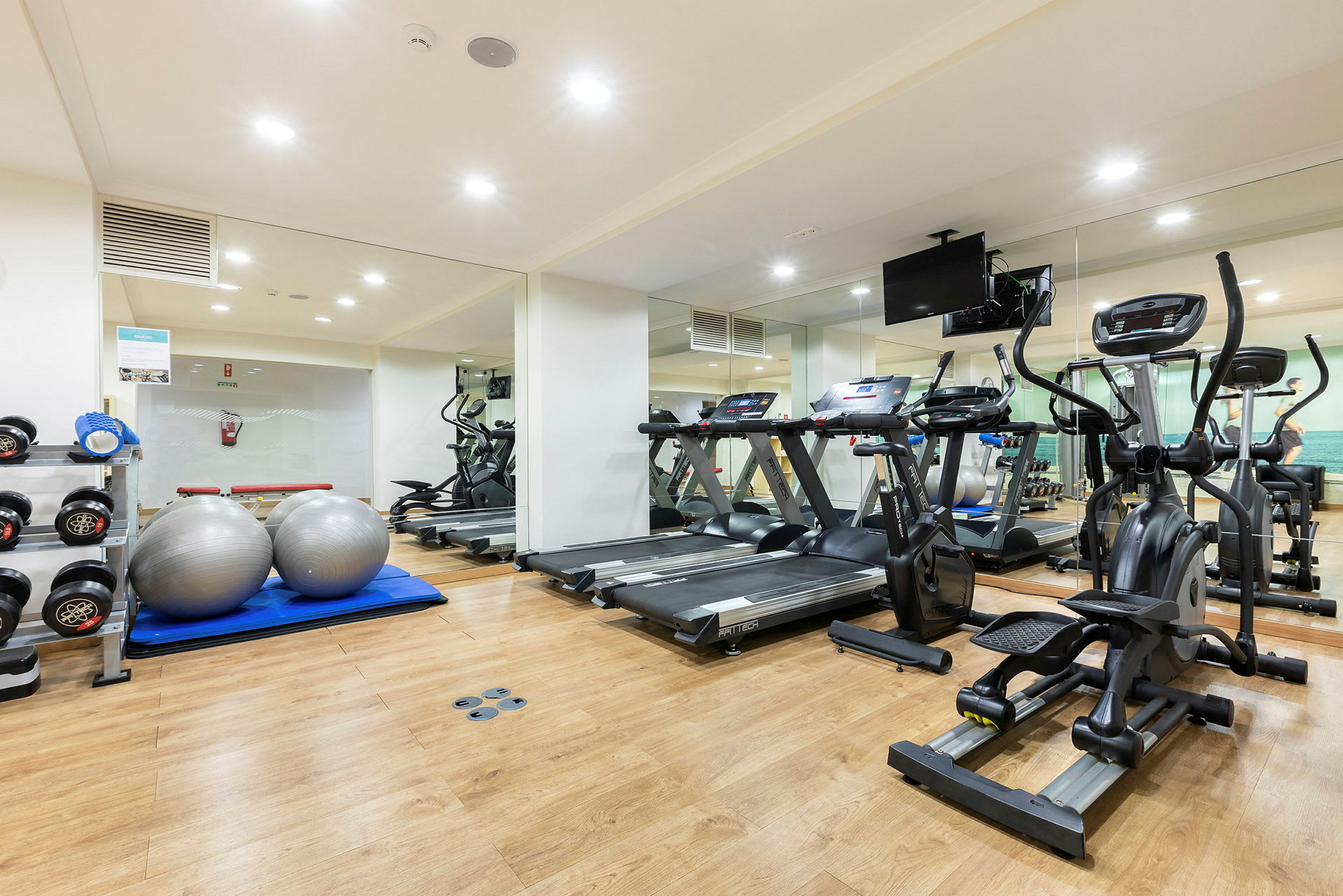 Ett gym med träningsmaskiner, hantlar och pilatesbollar. (AI-genererad text)
