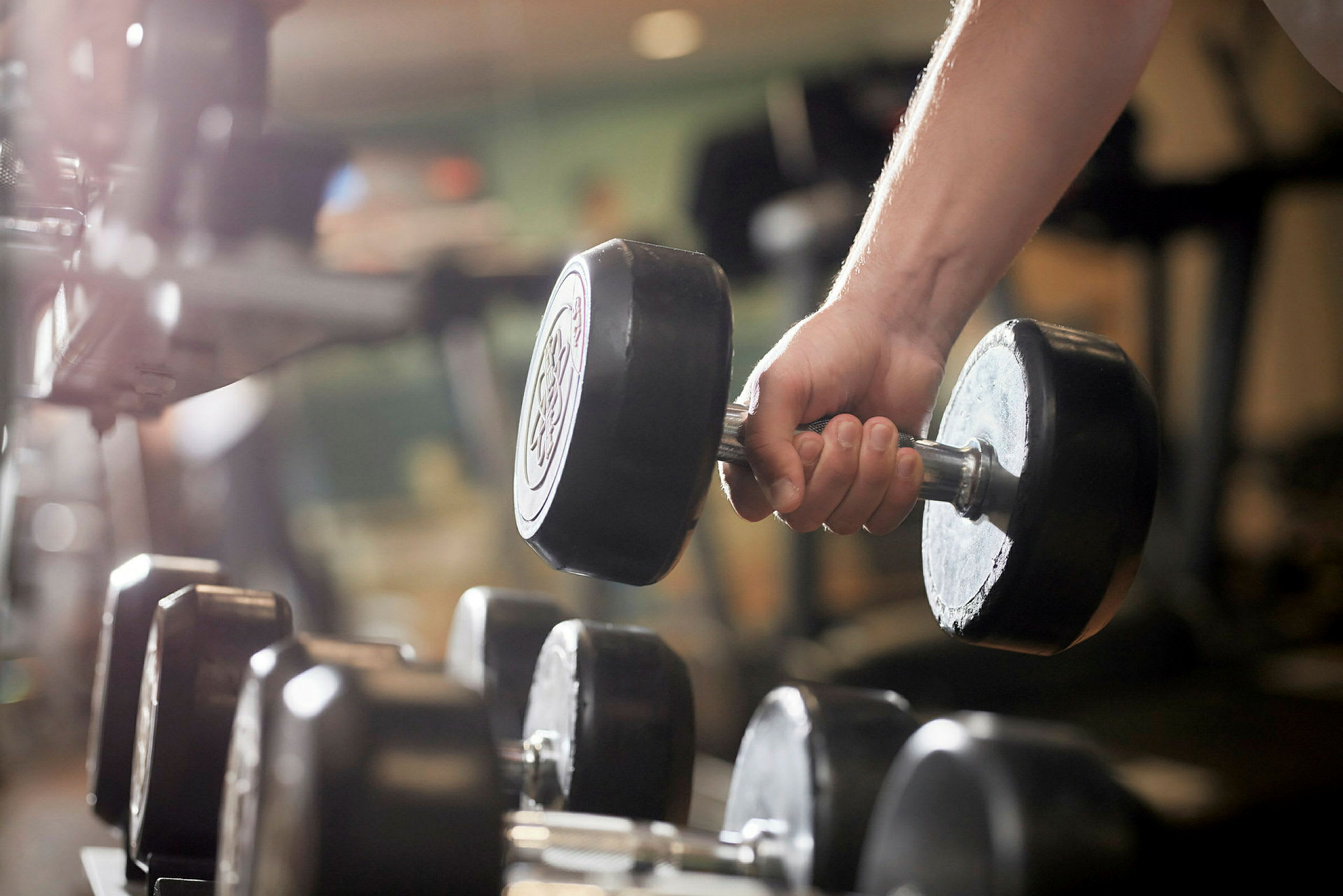 En hand håller i en hantel i ett gym. (AI-genererad text)