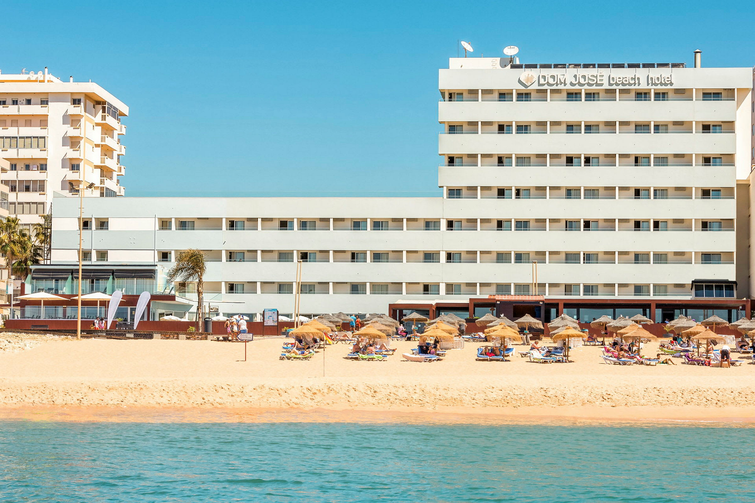 Hotell vid stranden med parasoller och solstolar. (AI-genererad text)
