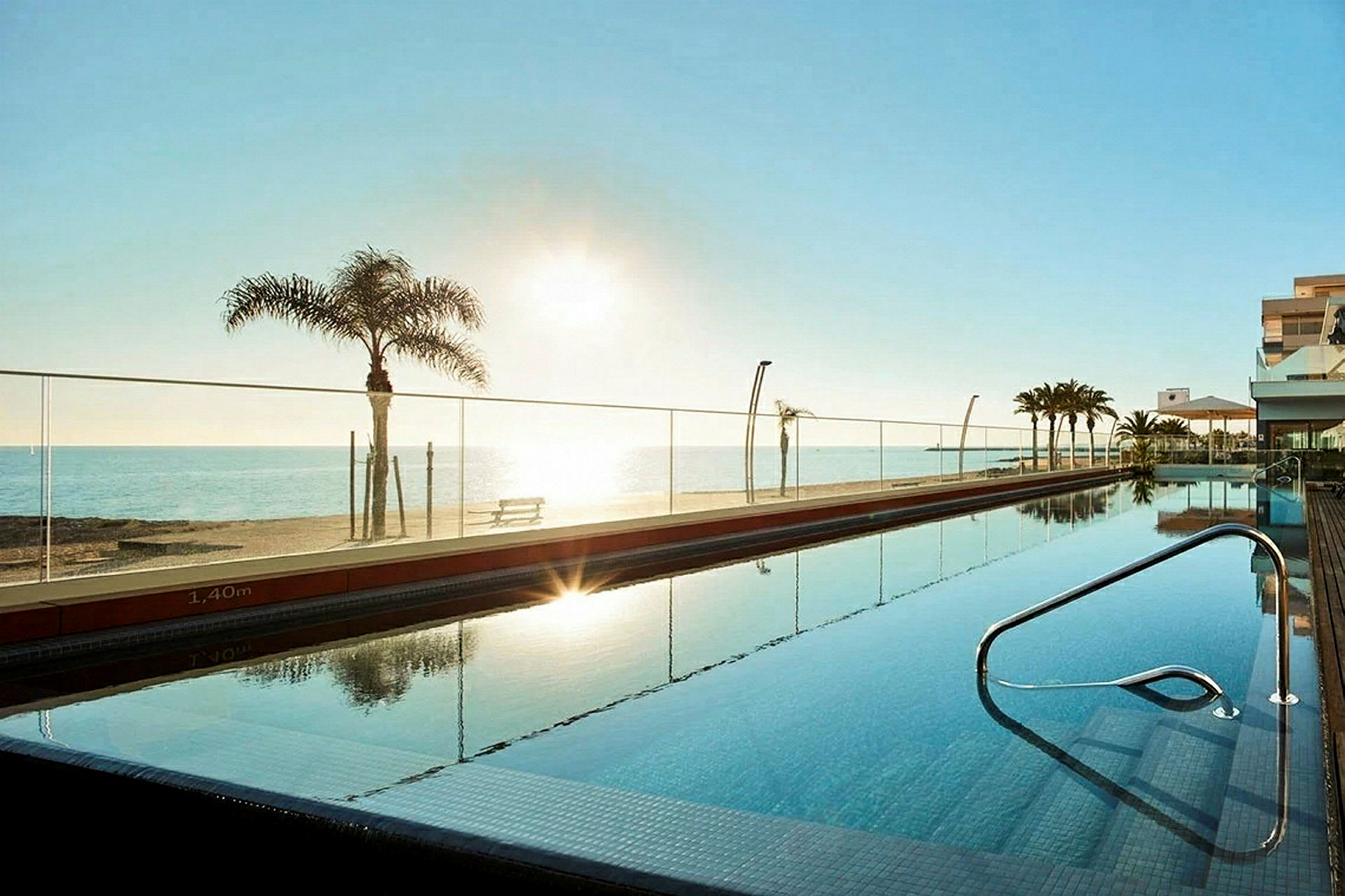 En swimmingpool vid ett hotell med utsikt över stranden och havet. (AI-genererad text)