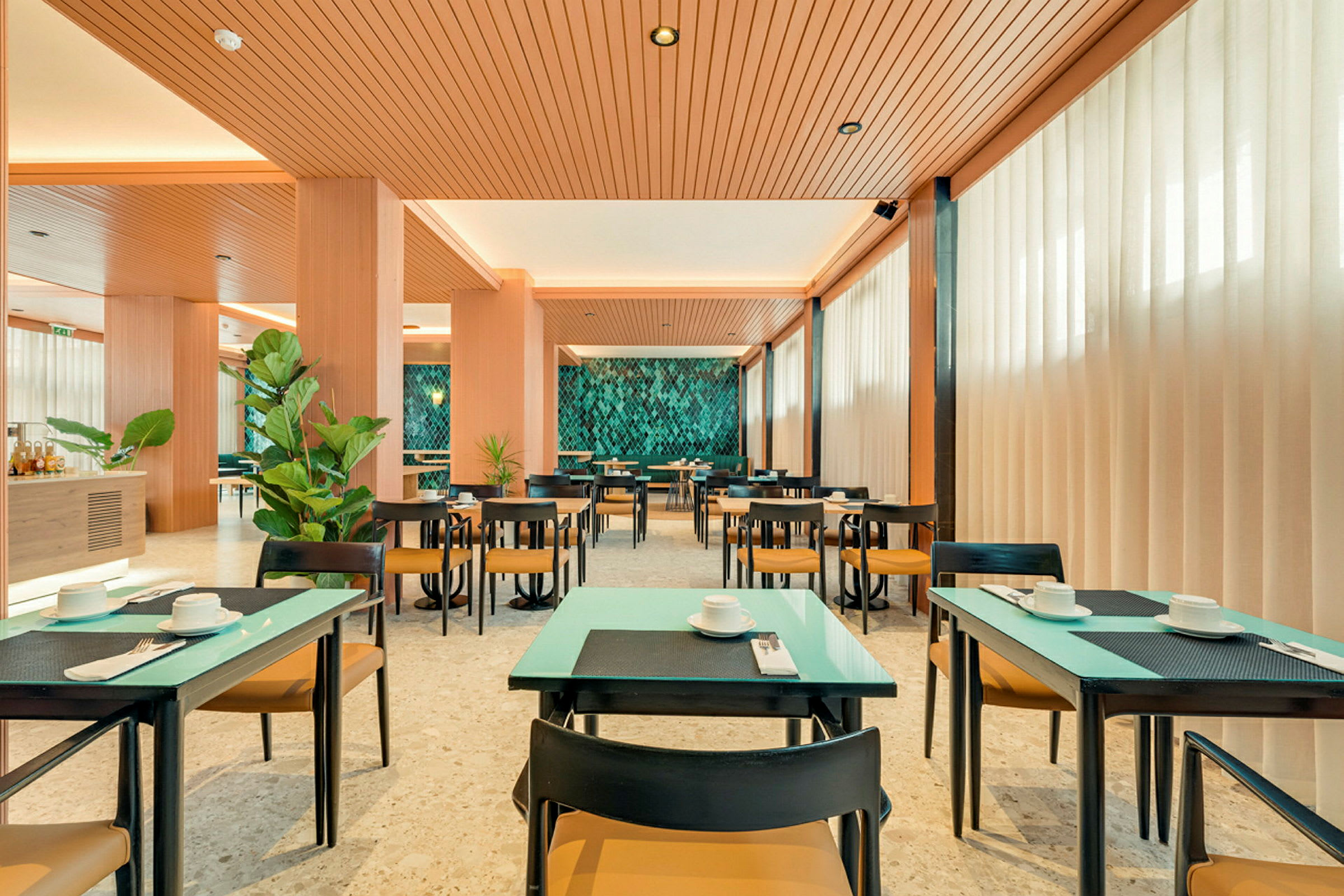 En ljus och modern restaurang med dukade bord, gröna växter och en dekorativ vägg. (AI-genererad text)