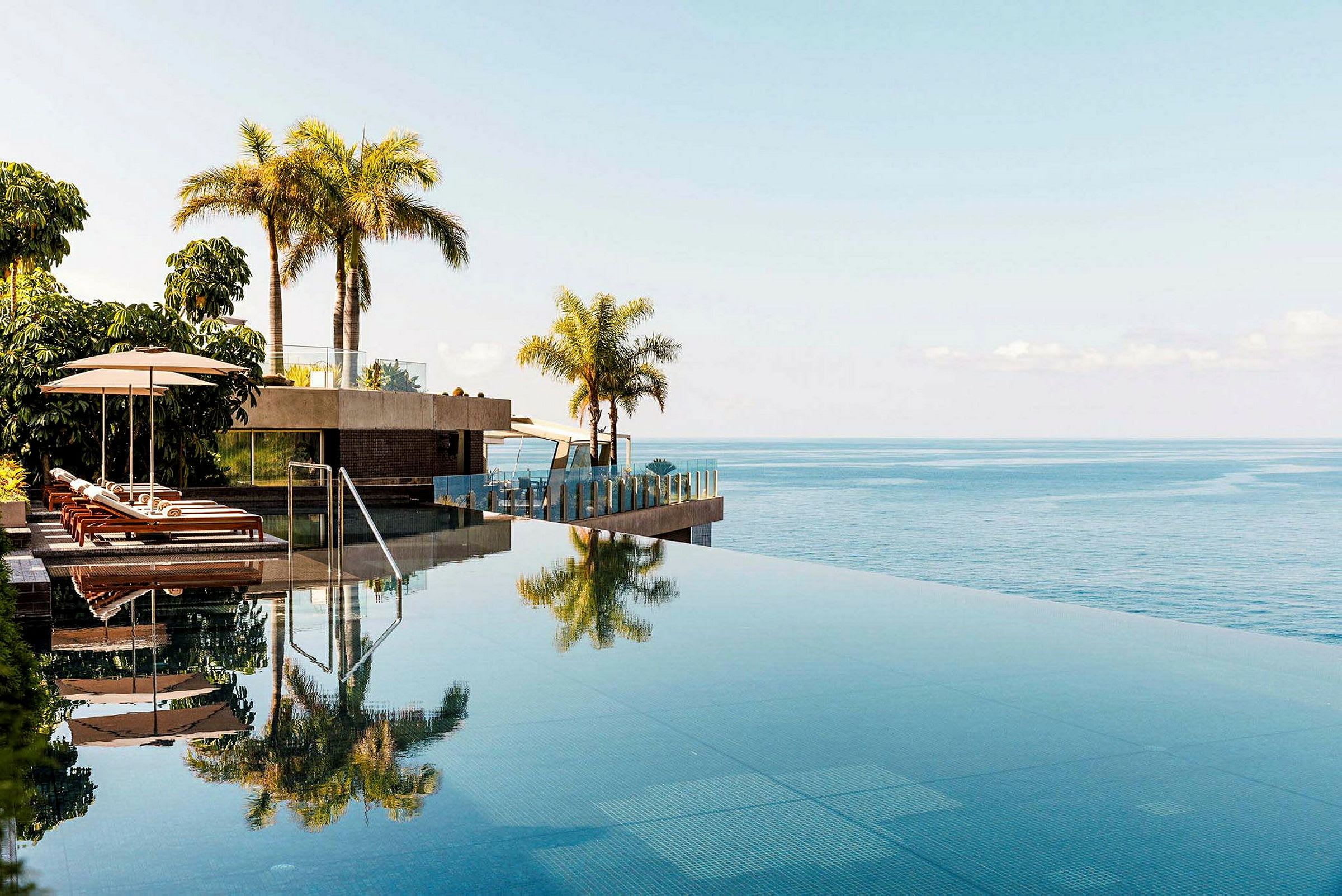 Infinitypool med solstolar och palmer, utsikt över havet. (AI-genererad text)