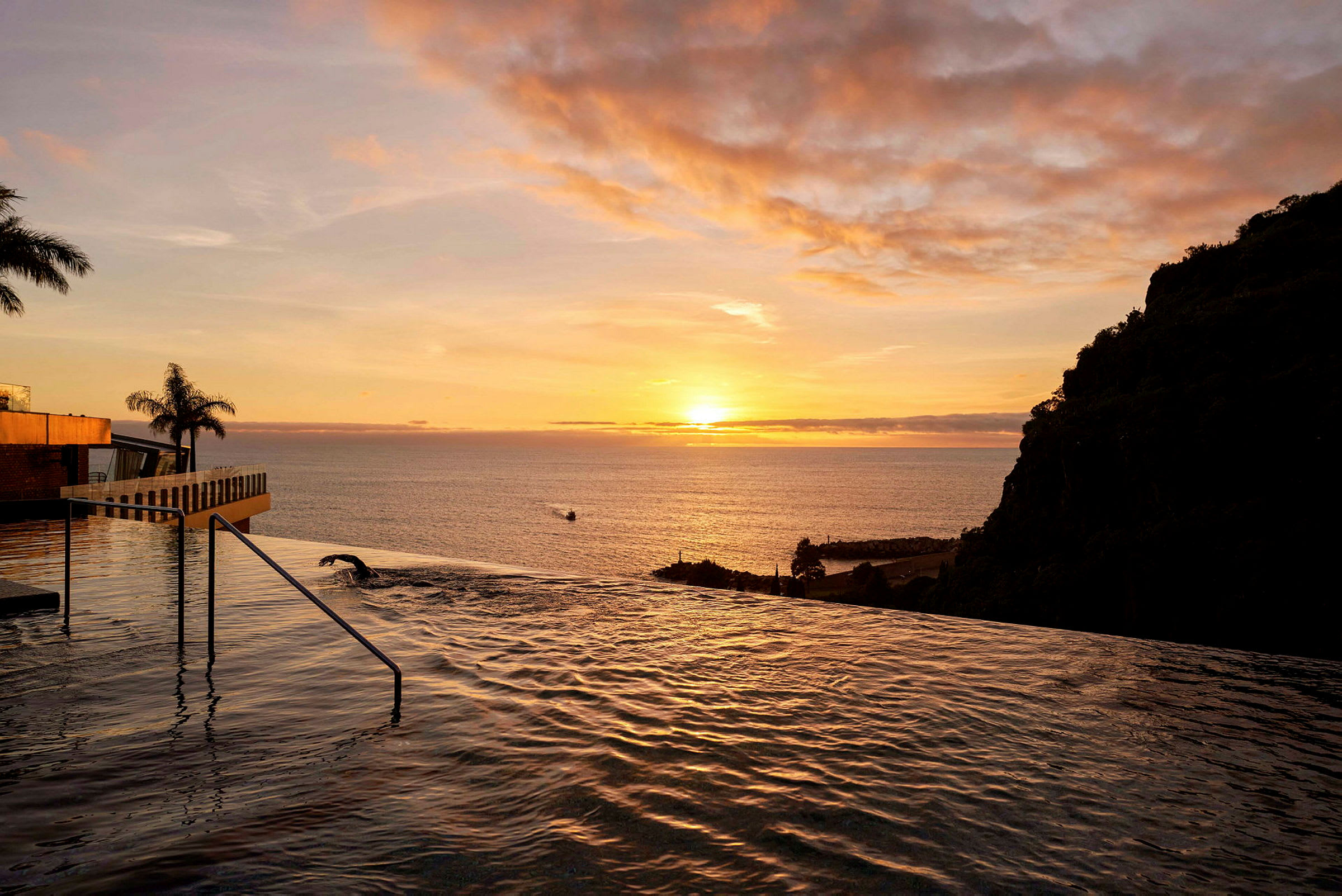 Utsikt över en infinitypool med havet och solnedgången i bakgrunden. (AI-genererad text)