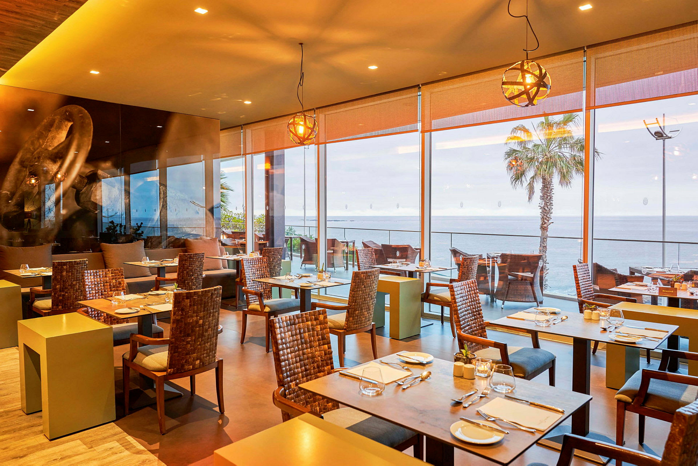 Restaurang med sittplatser och stora fönster mot havet. (AI-genererad text)