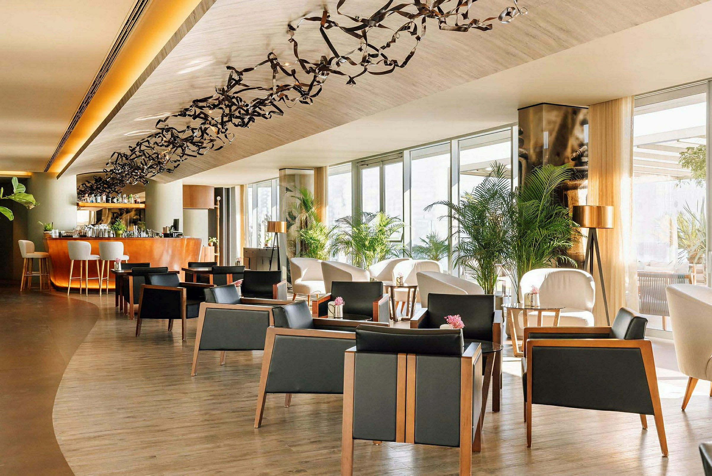 Ett elegant loungeområde med stolar, bord och dekorativa växter. En bardisk i bakgrunden. (AI-genererad text)