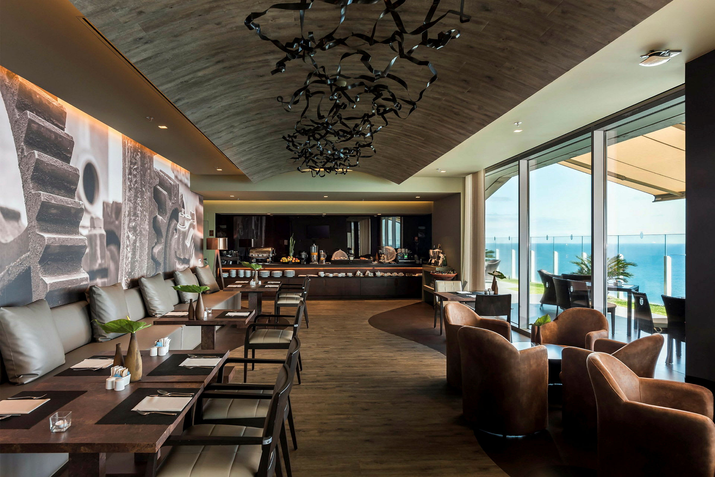 En modern restaurang med sittplatser och ett buffébord vid fönster med utsikt över havet. (AI-genererad text)